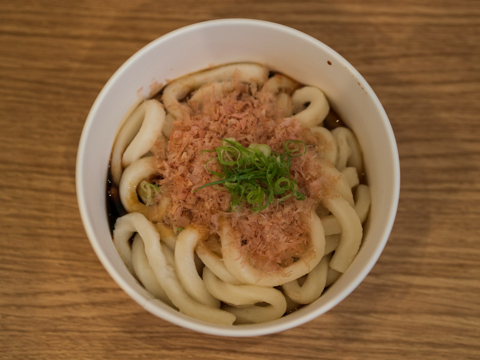 Noodles udon con scaglie di bonito e cipolle verdi in una ciotola bianca