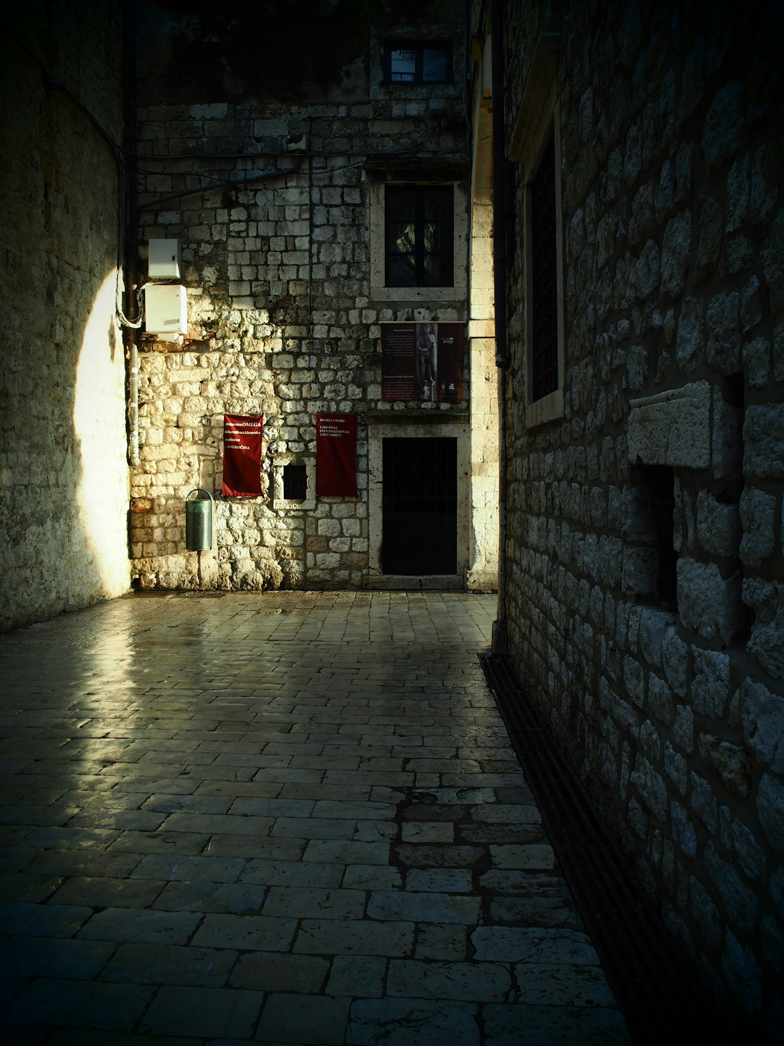 Calle tranquila con muros de piedra y sombras
