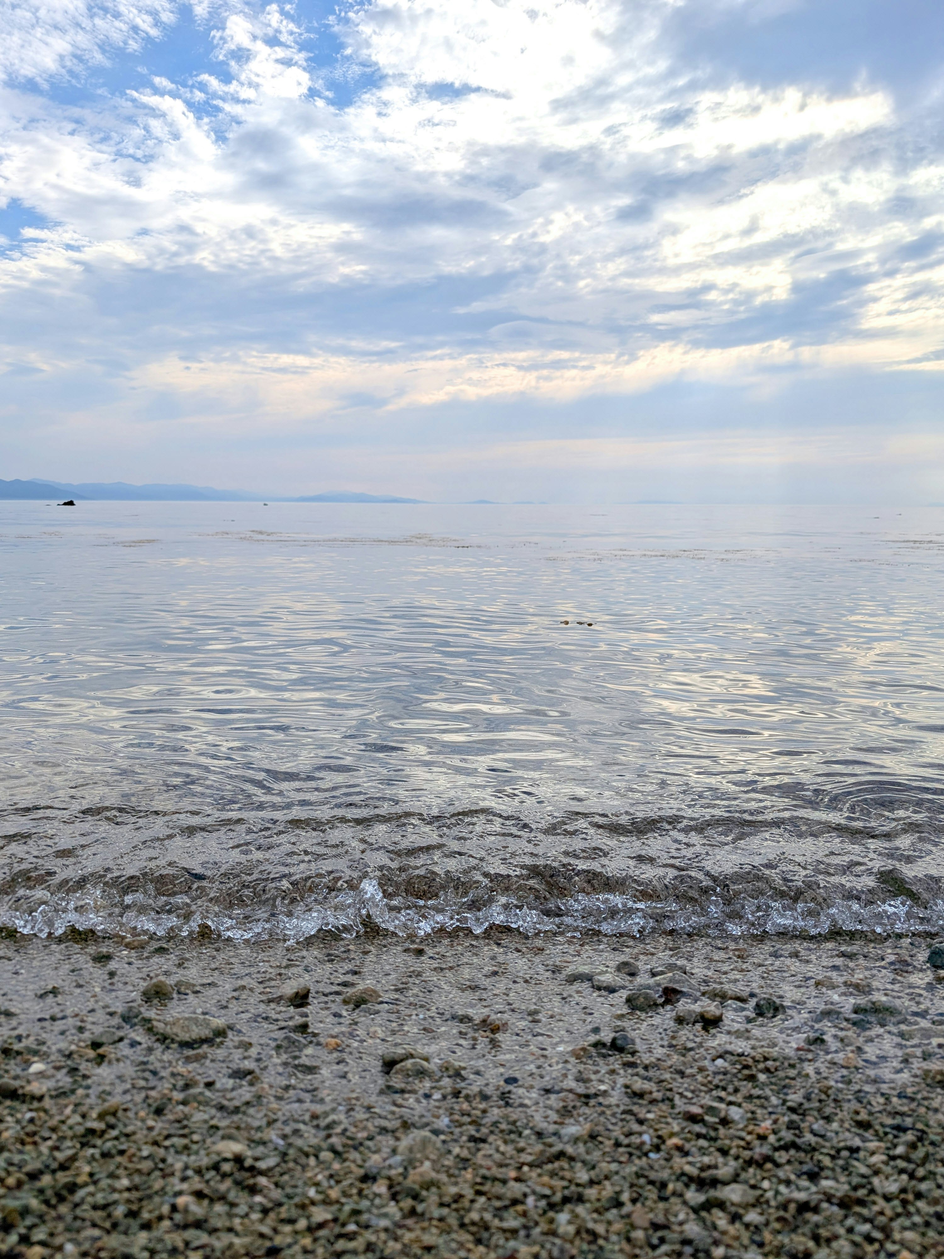波打つ透明感のある砂浜と遠くの海面