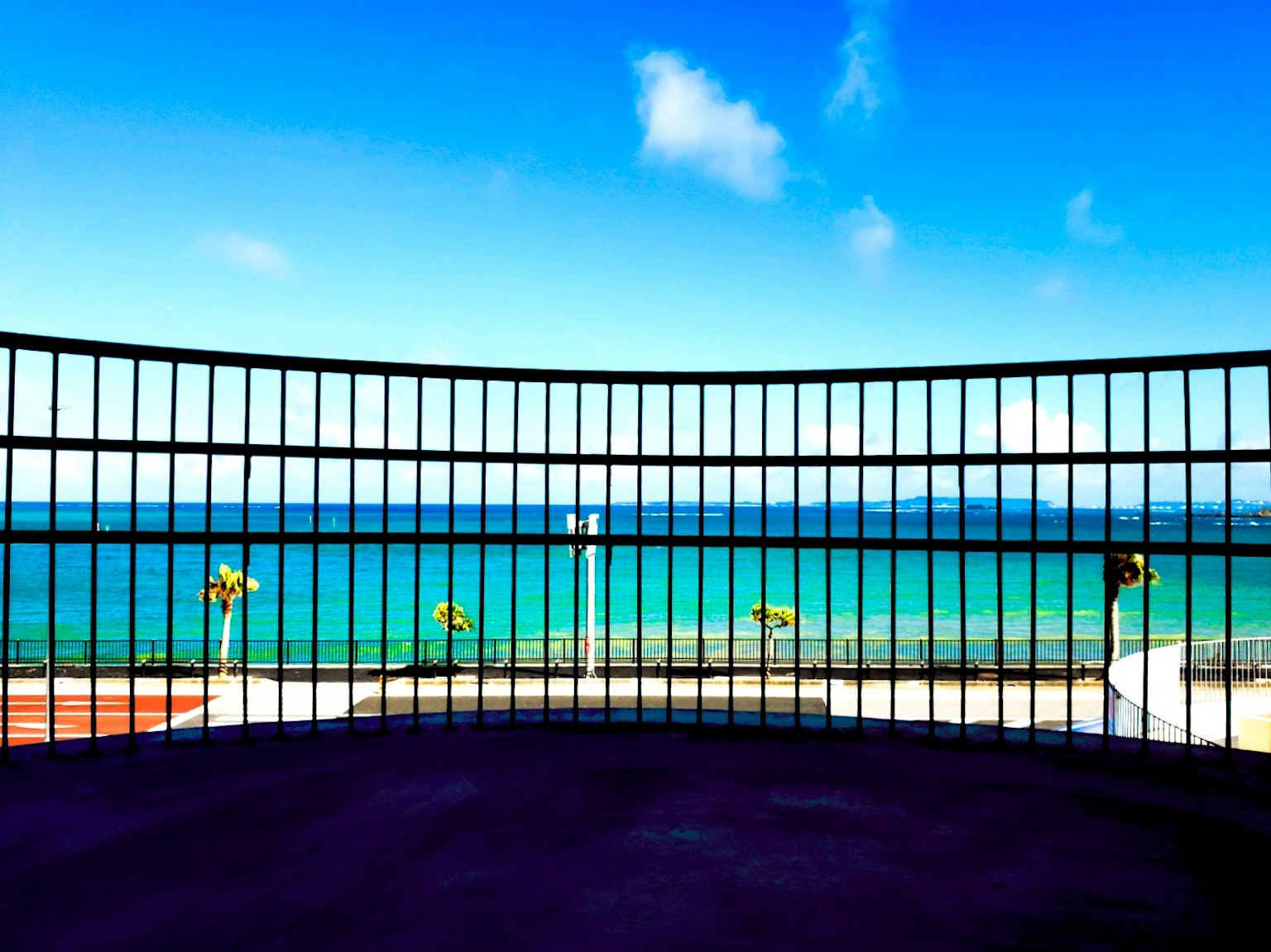 Recinzione in ferro che incornicia una vista dell'oceano blu e del cielo