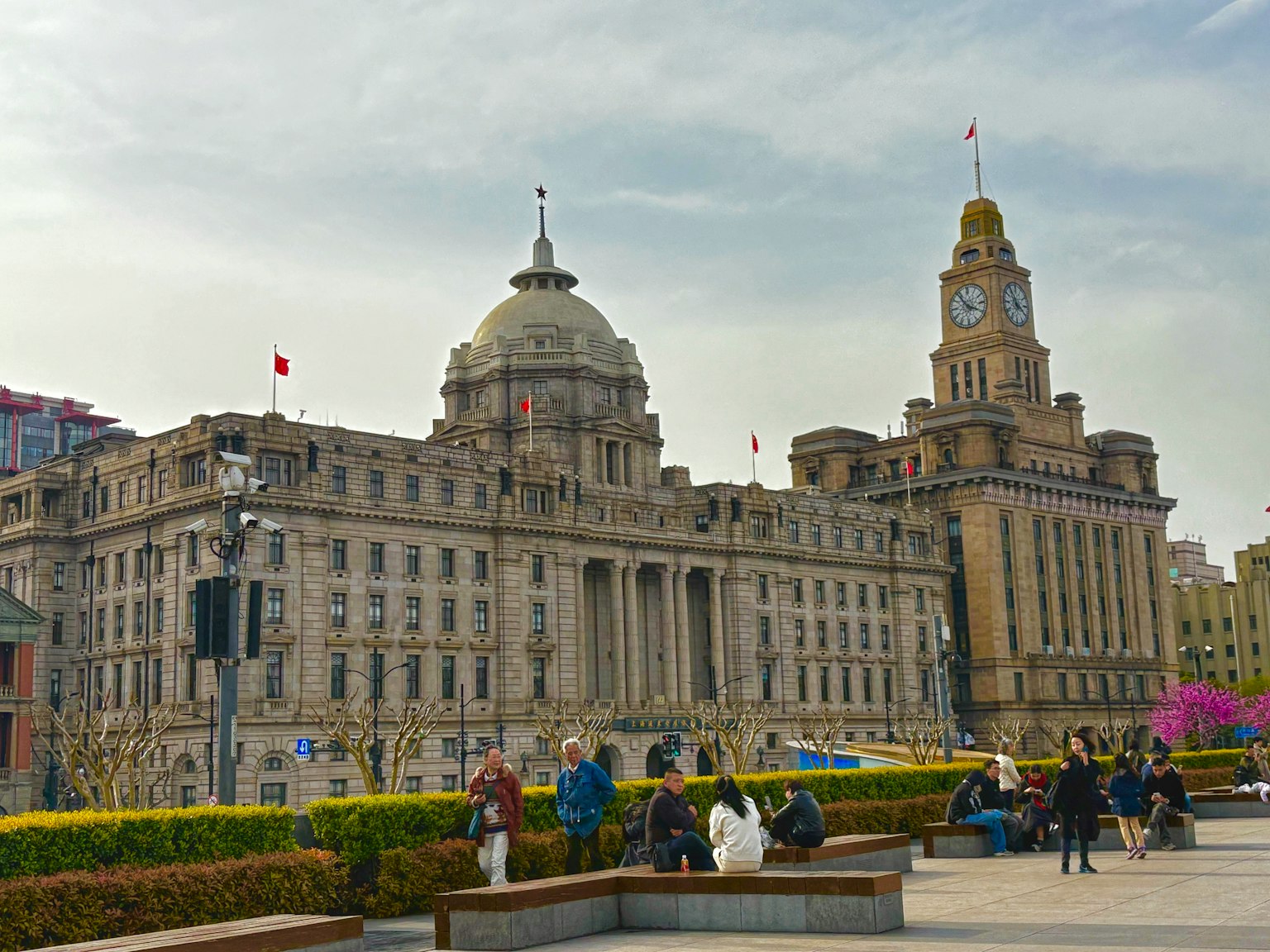 Bangunan bersejarah di Bund Shanghai dengan orang-orang berkumpul di alun-alun