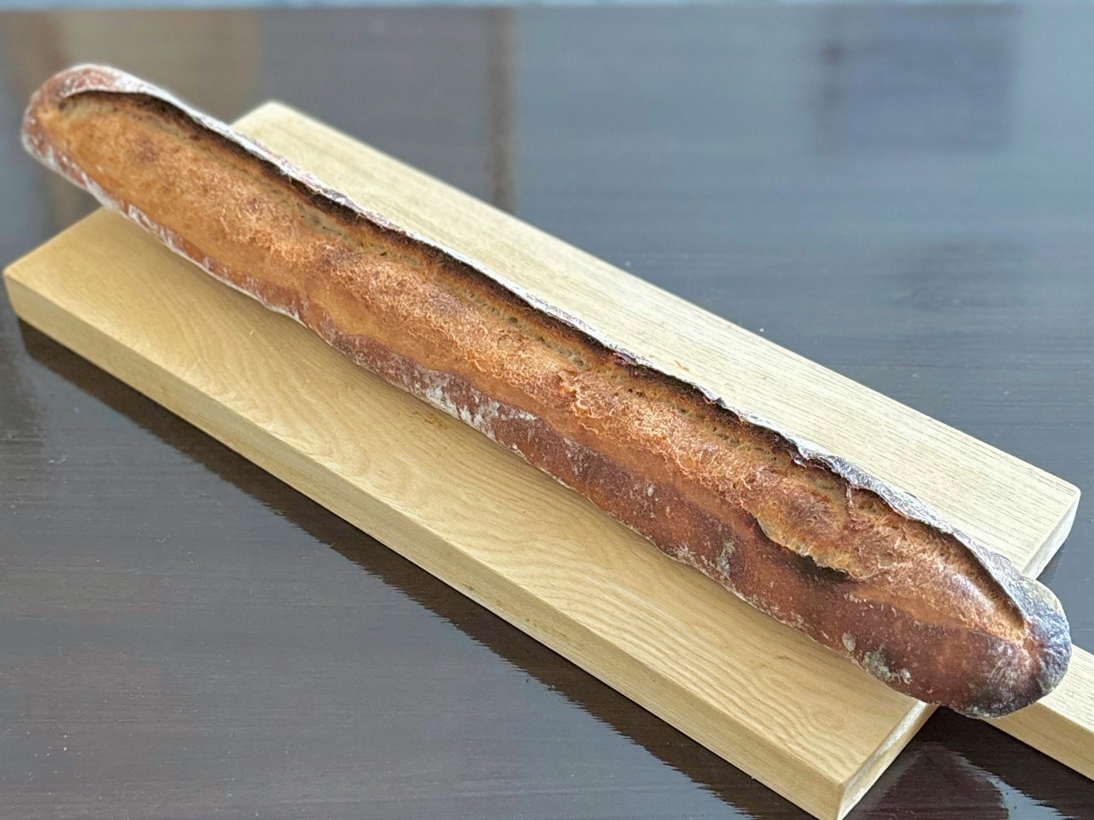 A long baguette placed on a wooden board