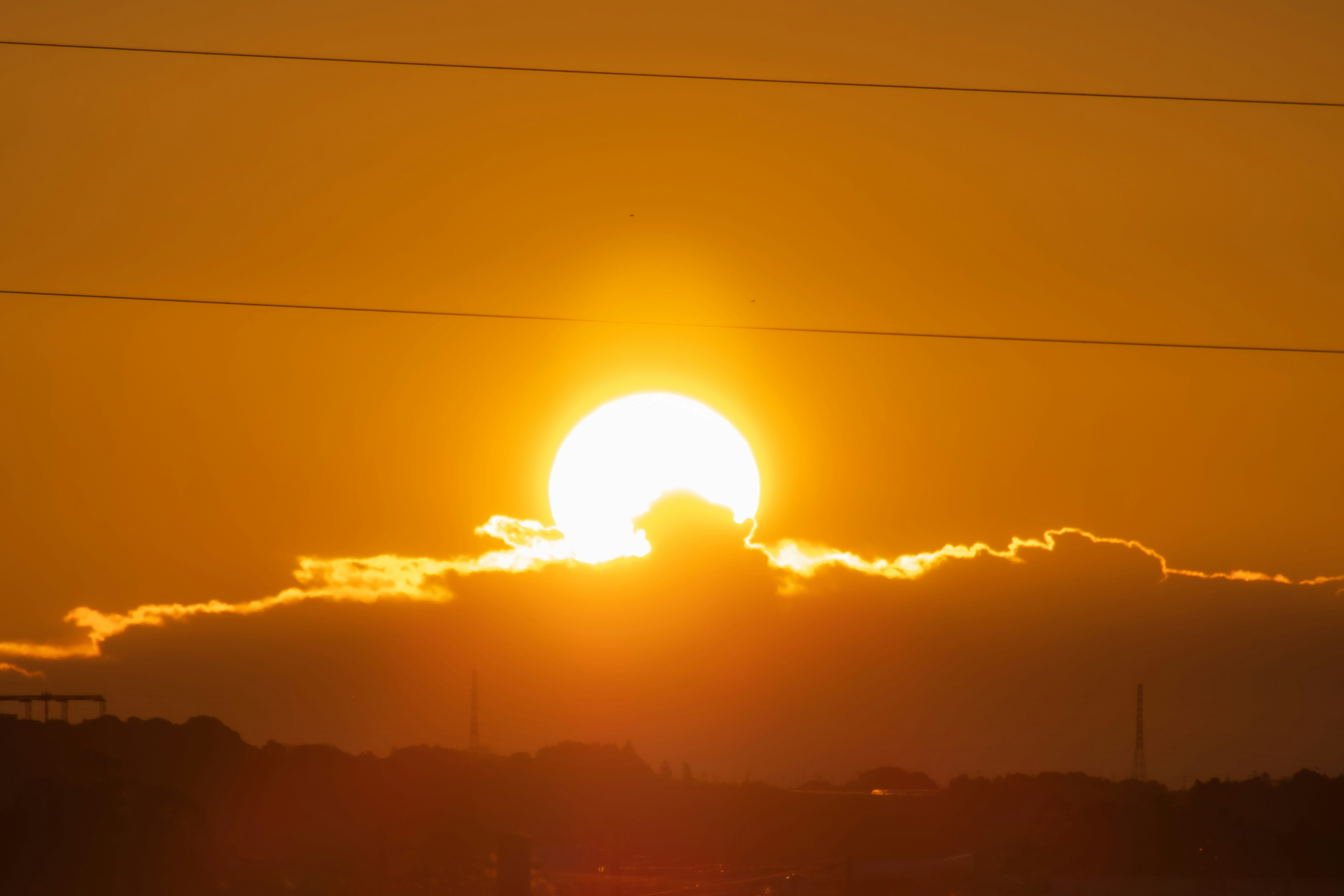 夕焼けの空に浮かぶ太陽と雲のシルエット