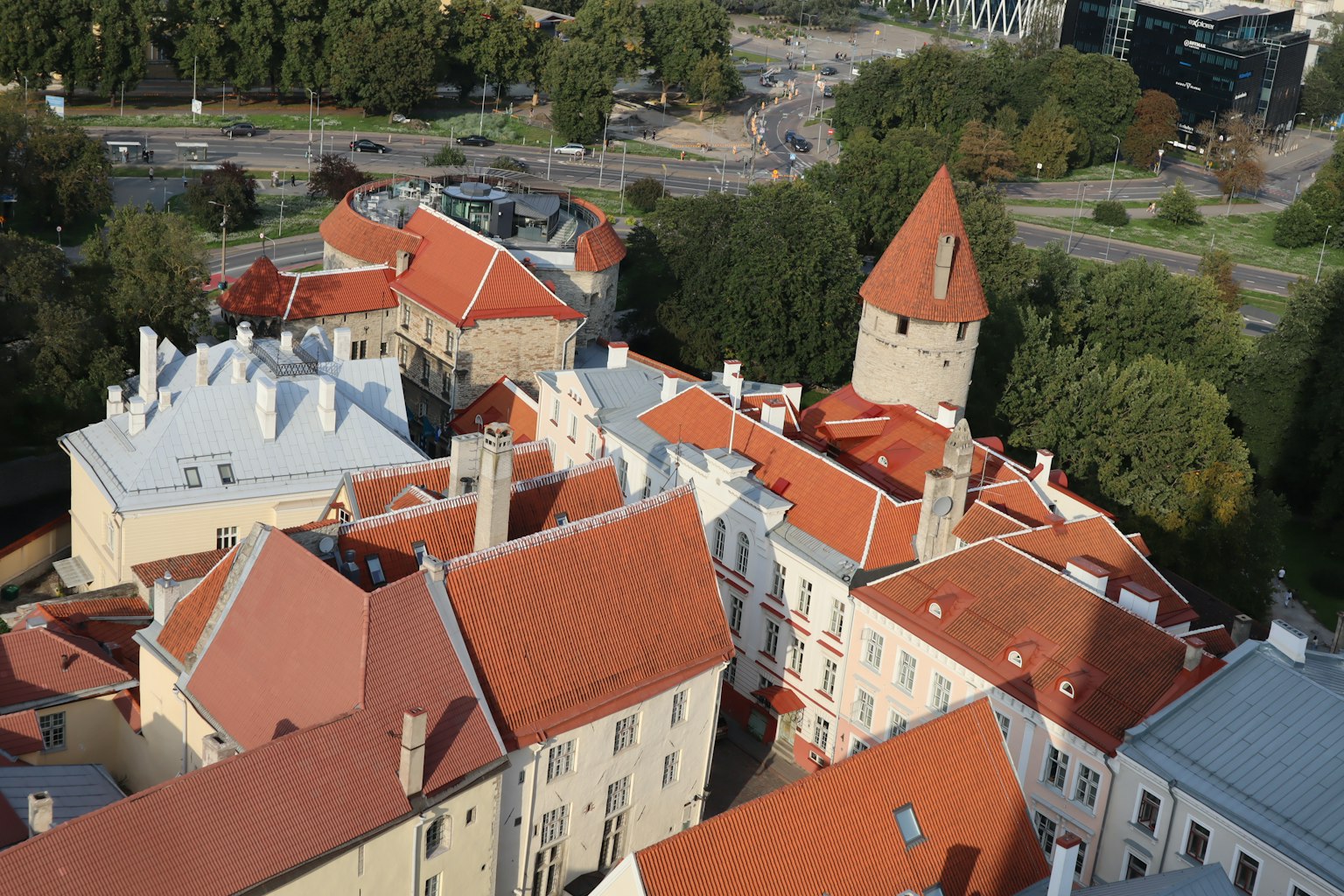 Vista aérea de edificios históricos con techos rojos rodeados de árboles y arquitectura moderna