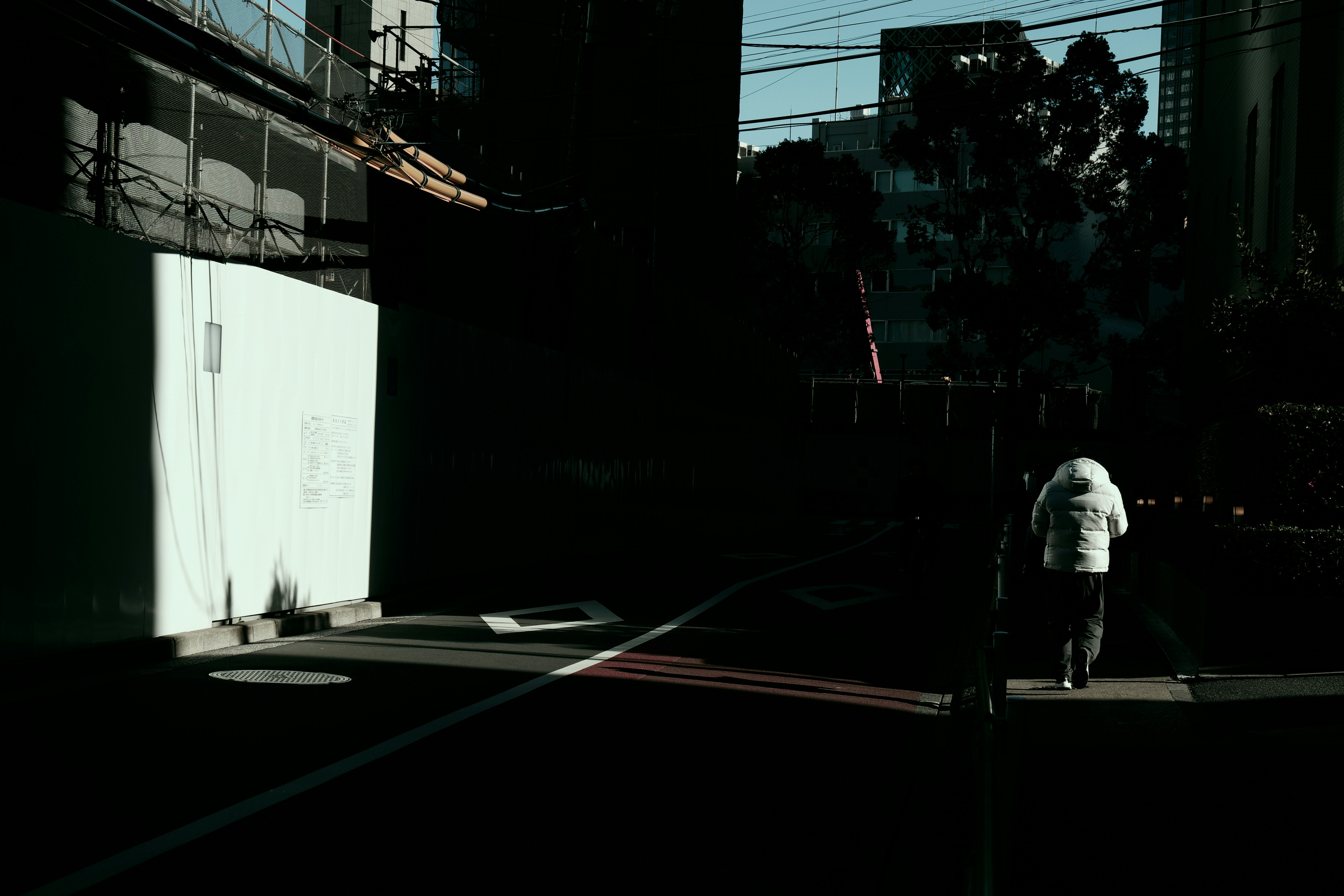 silhouette of a person walking along a narrow alley by a wall