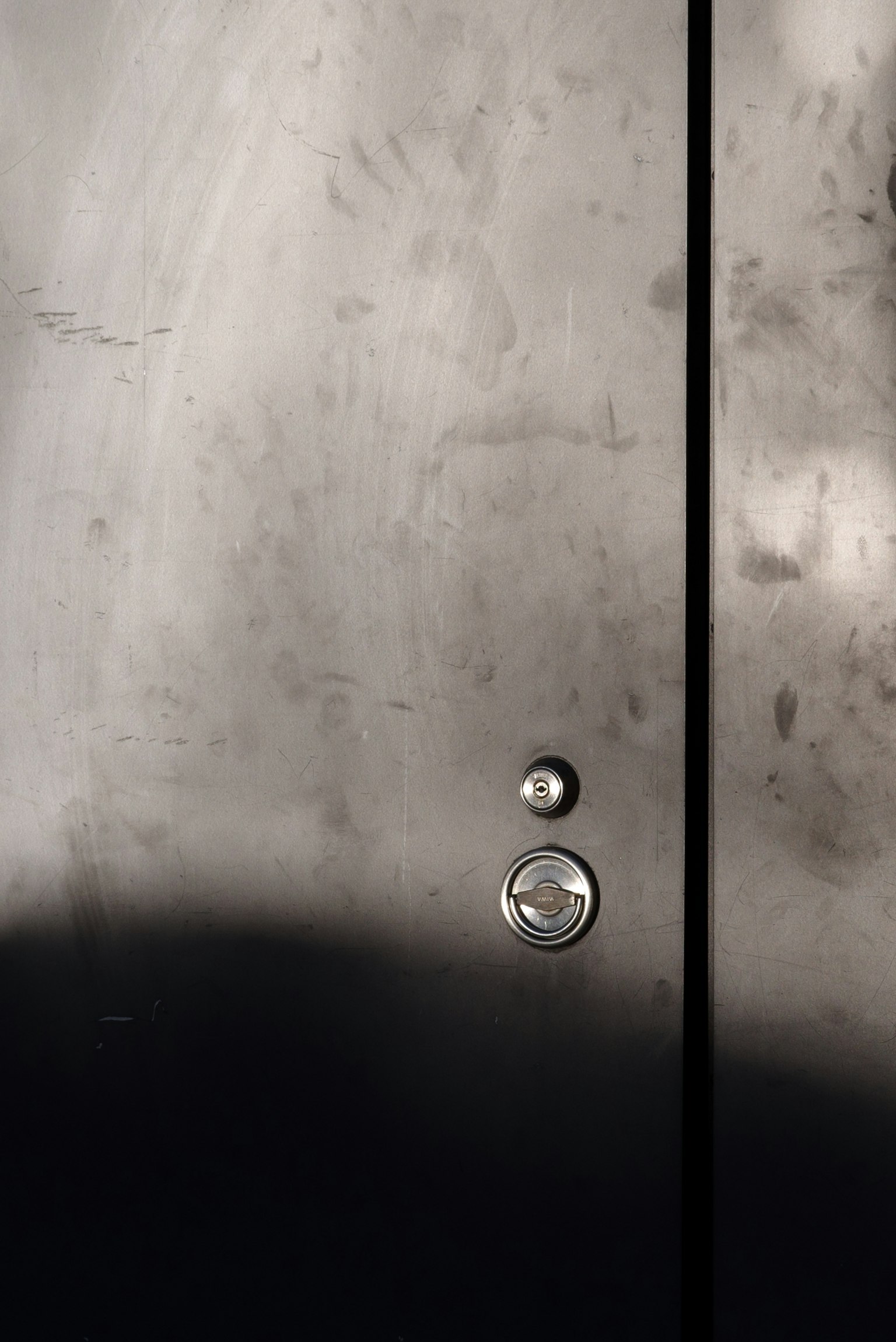 Close-up of a black metal door featuring a round knob and a small circular keyhole