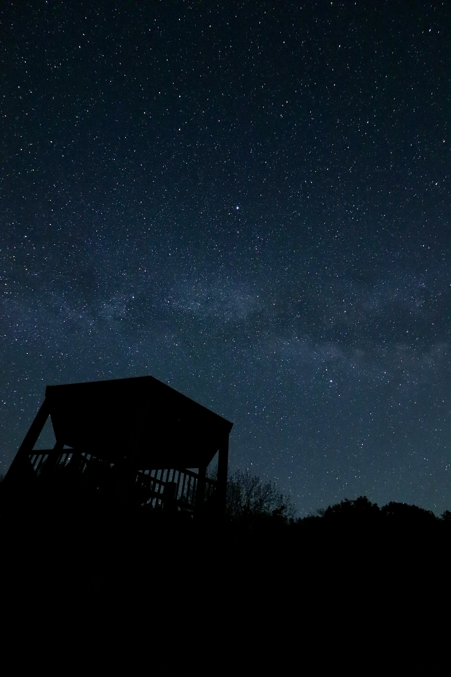 Paisaje nocturno con cielo estrellado y la silueta de una cabaña