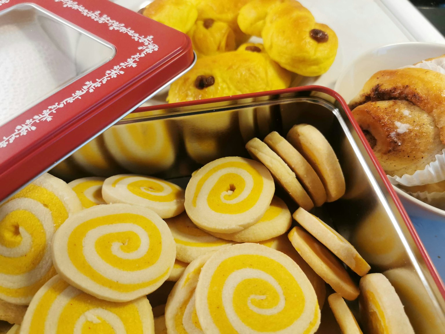 Biscuits en spirale jaunes dans une boîte rouge avec d'autres pâtisseries en arrière-plan