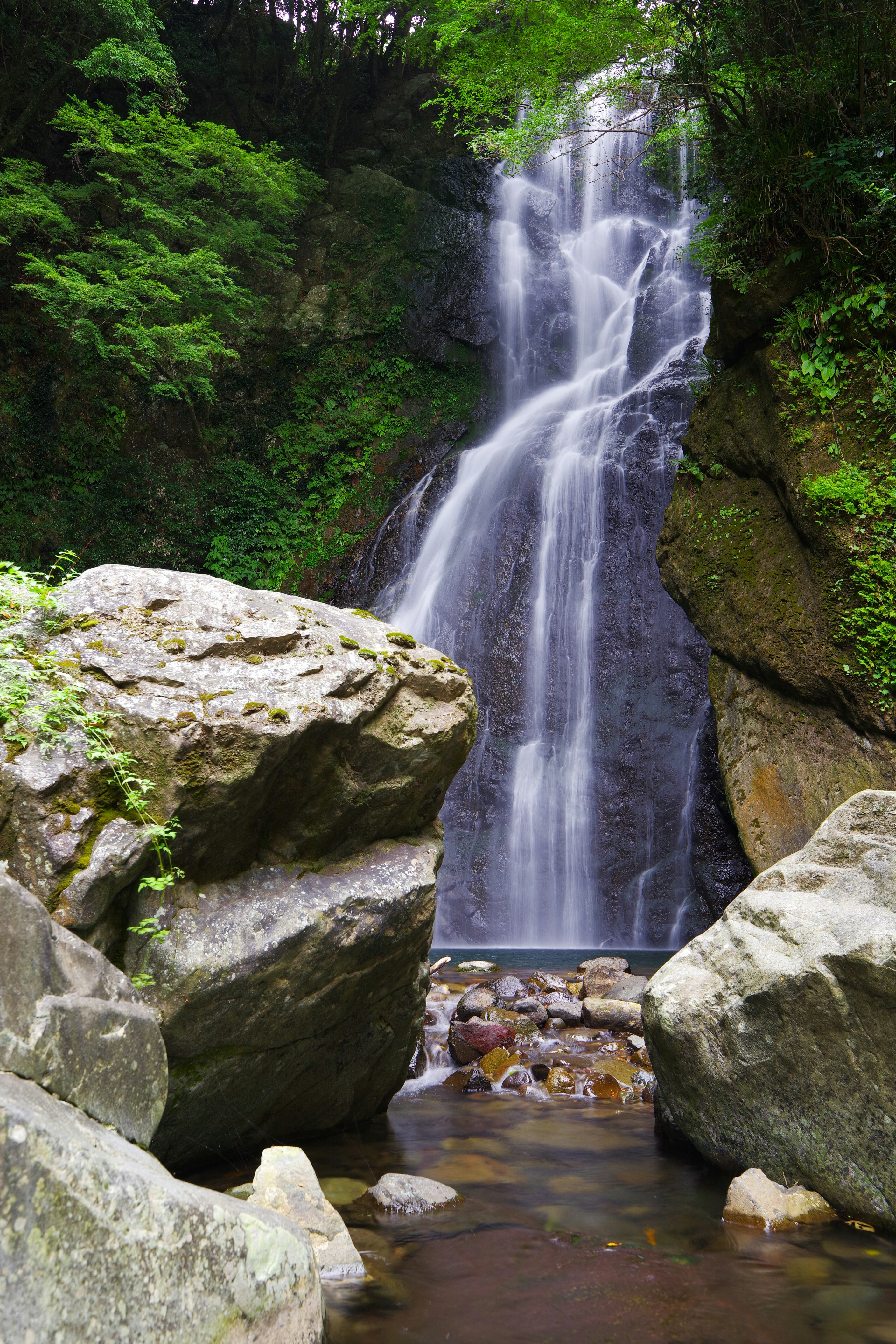 Air terjun di antara bebatuan dan aliran sungai hutan