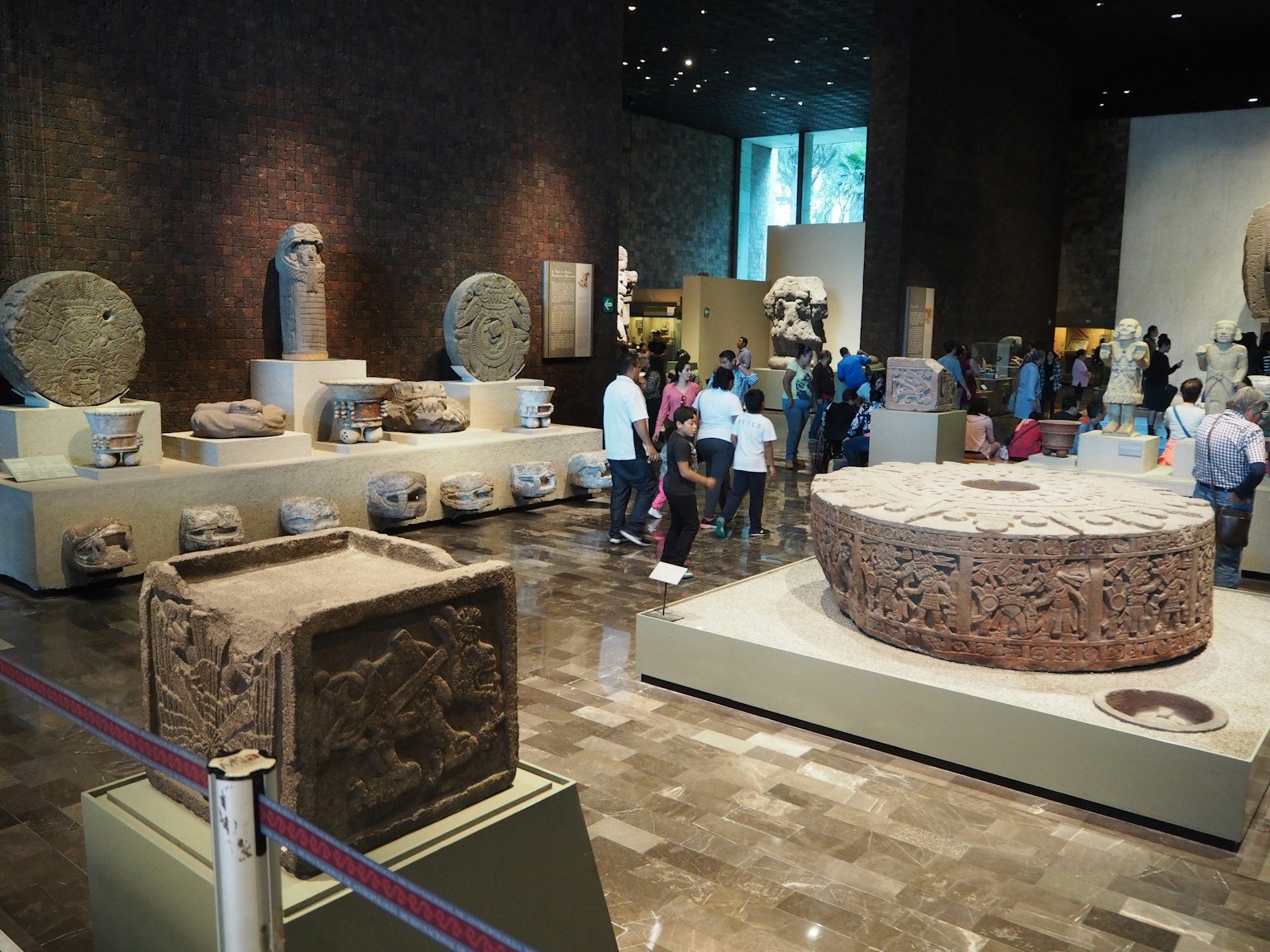 Archäologischer Ausstellungsraum mit antiken Steinartefakten und Besuchern