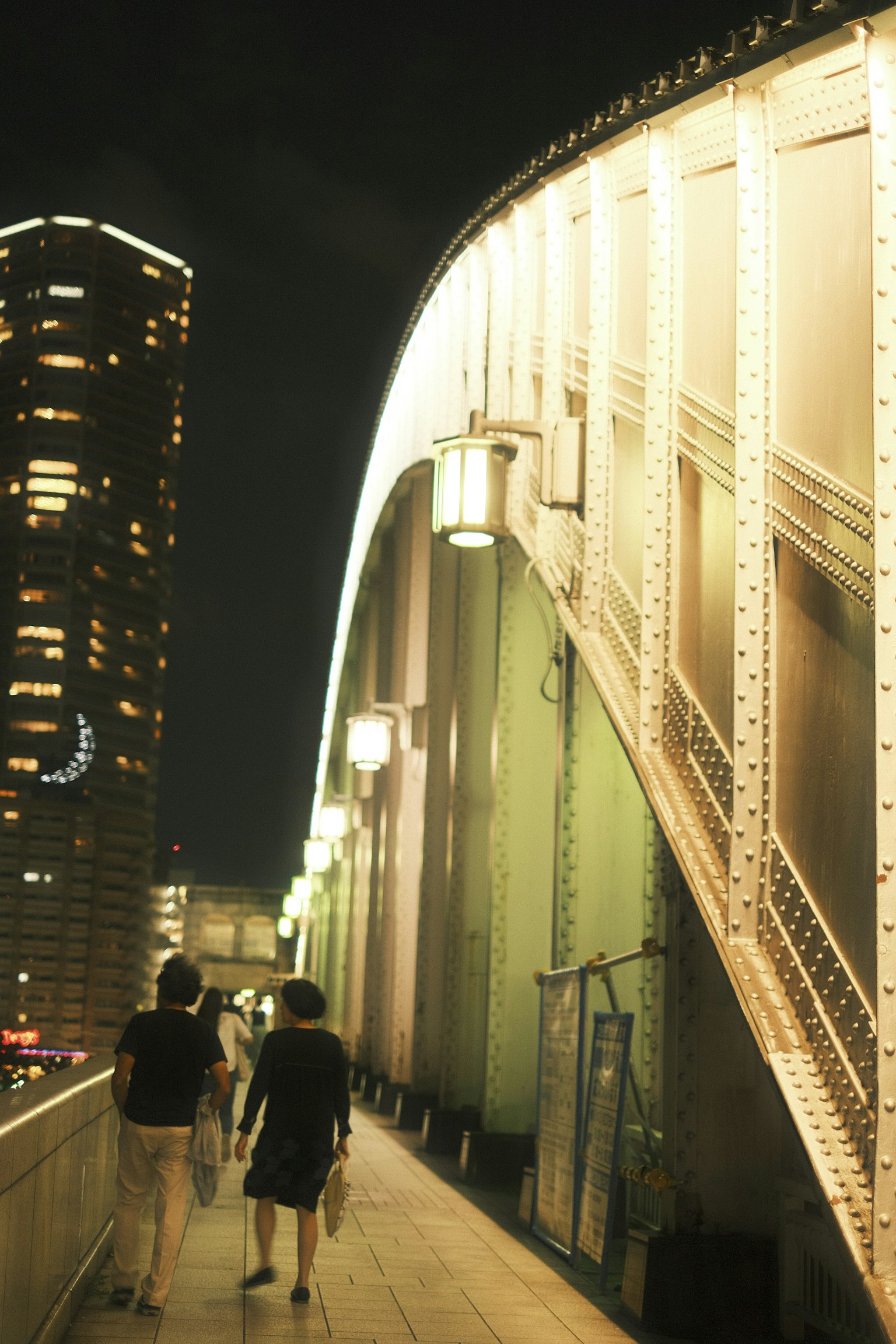 Personas caminando en un puente por la noche con faroles brillantes