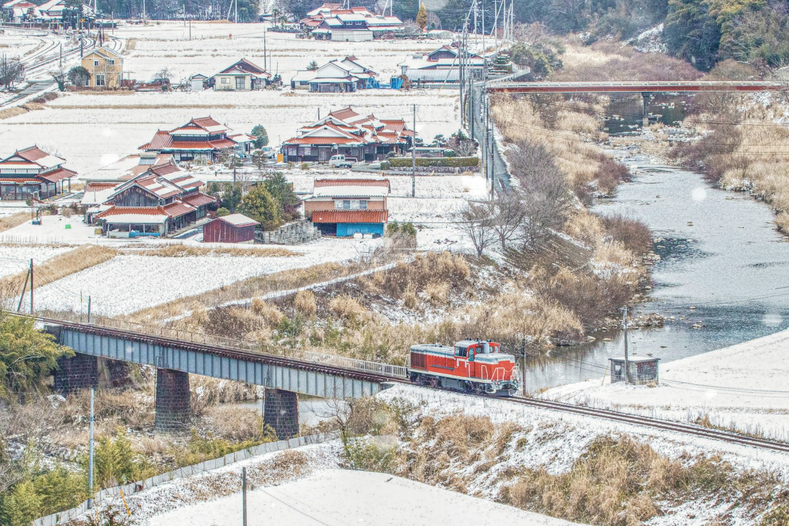 Tren rojo recorriendo un paisaje rural cubierto de nieve