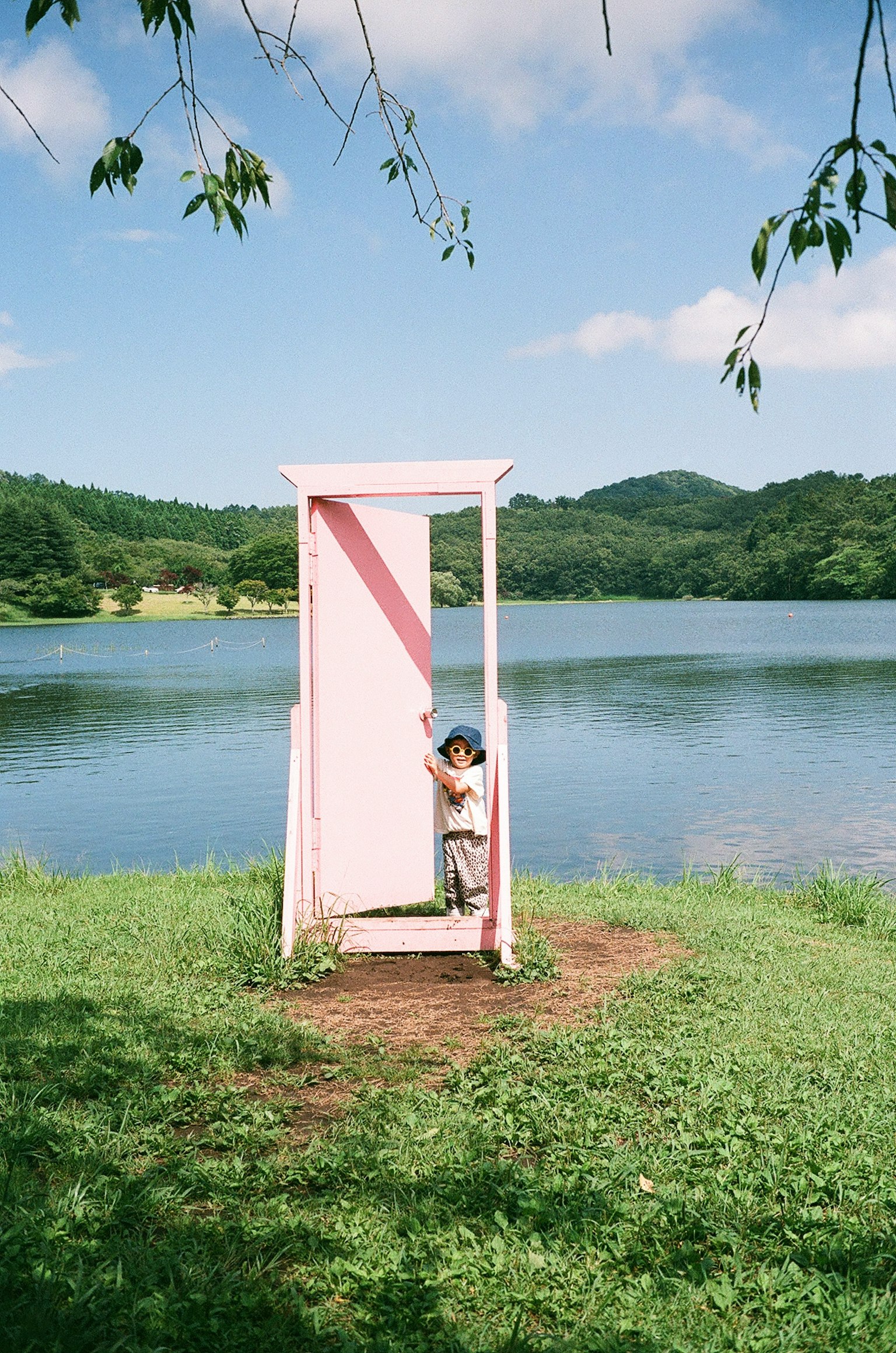 Child standing in front of a pink door by the lake
