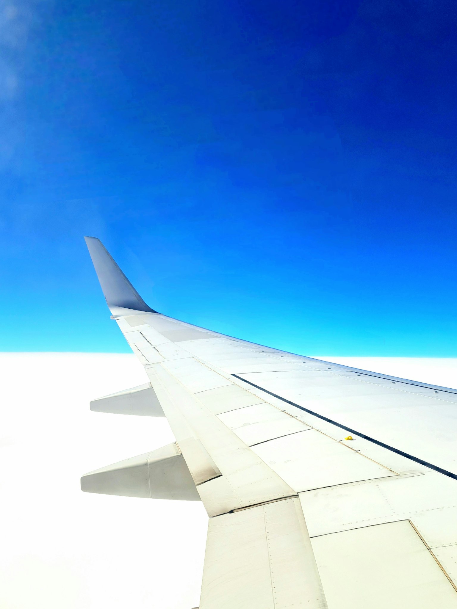 Un'ala di aereo contro un cielo blu brillante