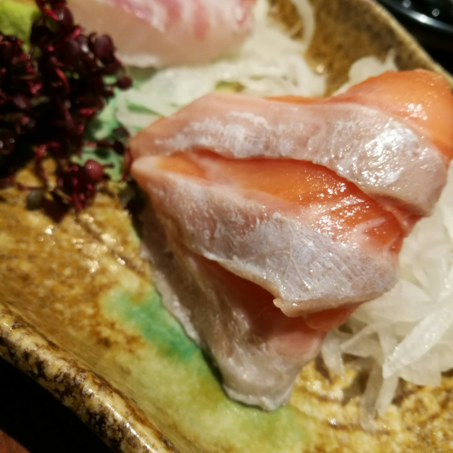 Piring sashimi yang disajikan dengan indah, dengan ikan merah muda dan putih