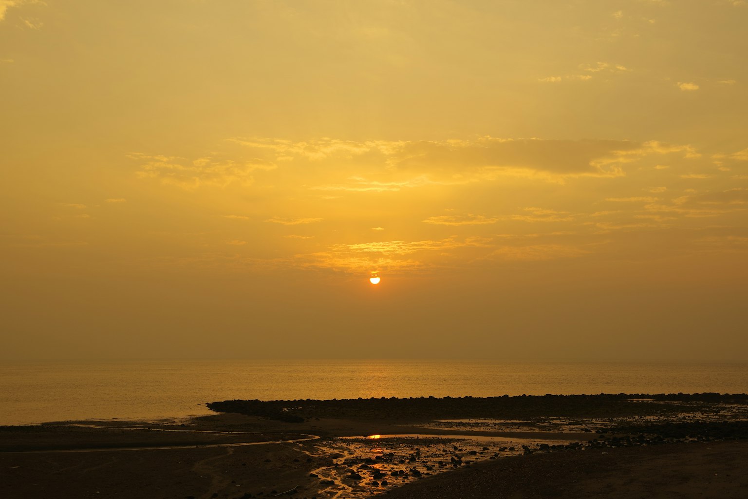 Golden sunset over calm sea with silhouetted rocks