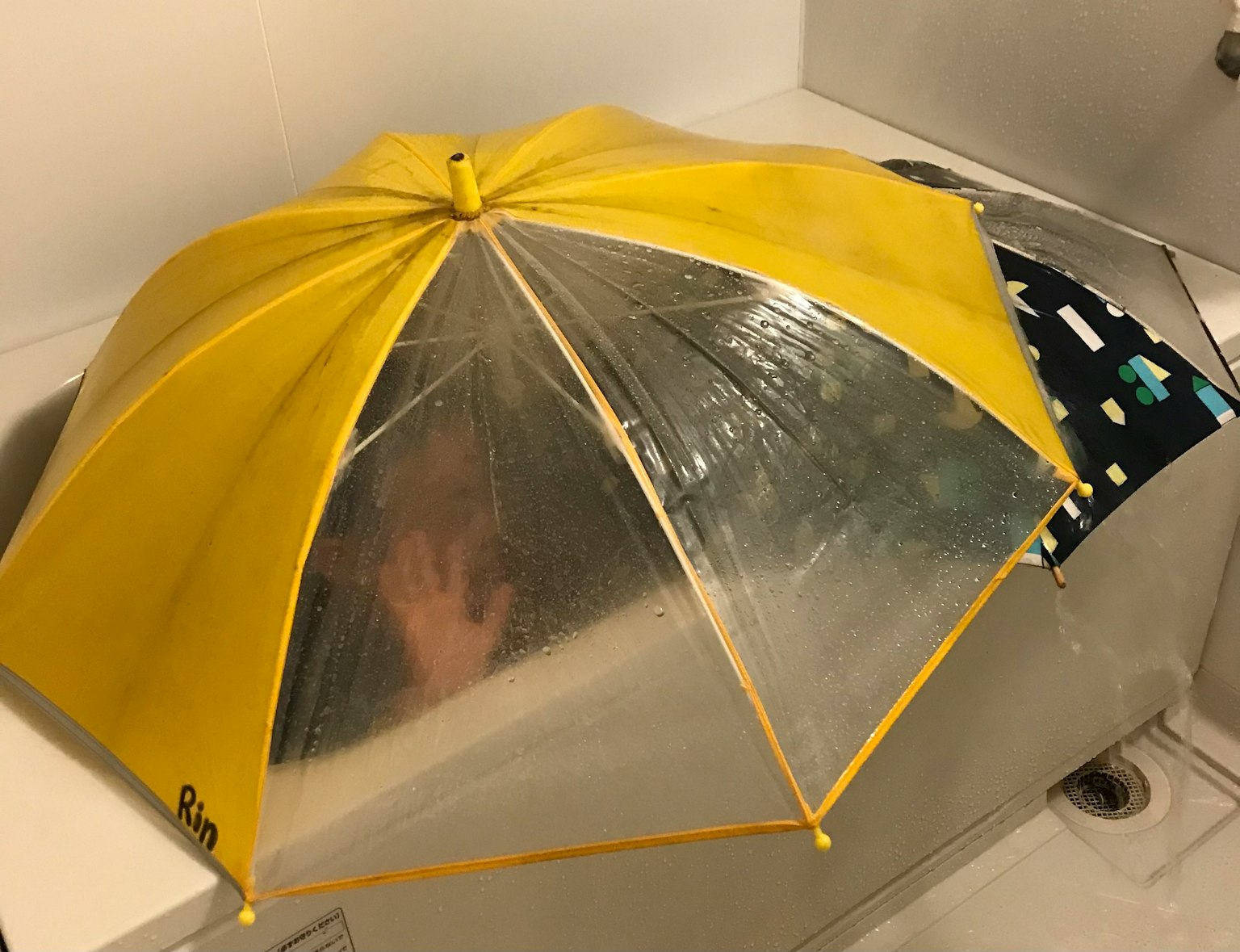 一个黄色和透明的雨伞放在水槽上