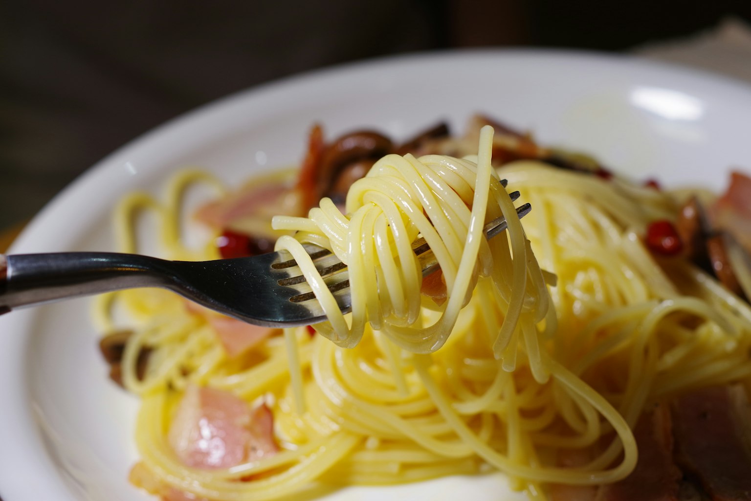 Plate of spaghetti with fork twirling noodles and ingredients