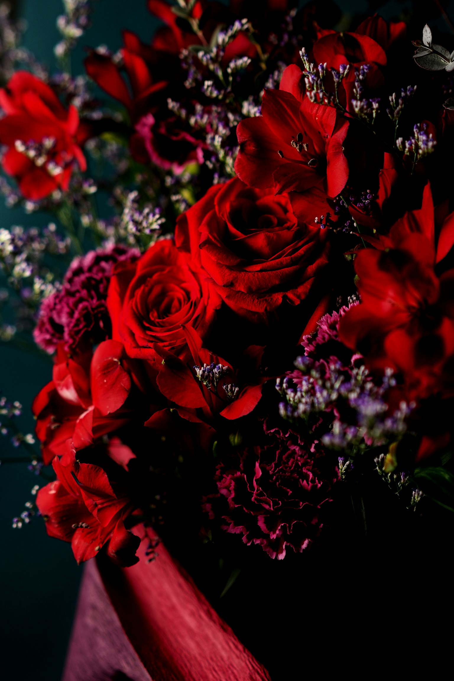 A bouquet featuring vibrant red roses and purple flowers beautifully arranged