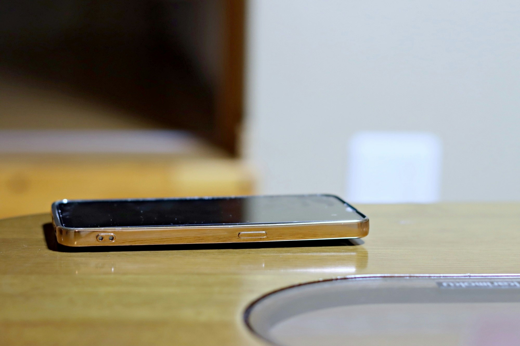 木の机の上に置かれたスマートフォンの横顔