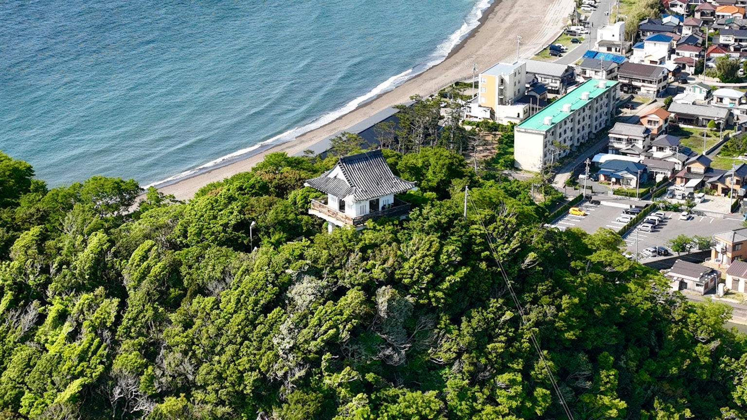 海岸附近綠意盎然的山丘上的寺廟與海灘和城鎮的美景