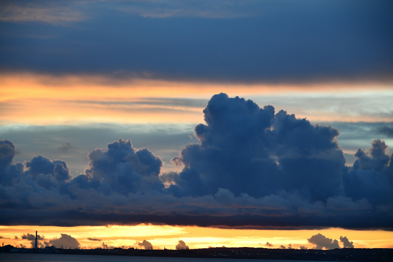 Dunkle Wolken in einem Sonnenuntergangshimmel mit orangefarbenem Licht
