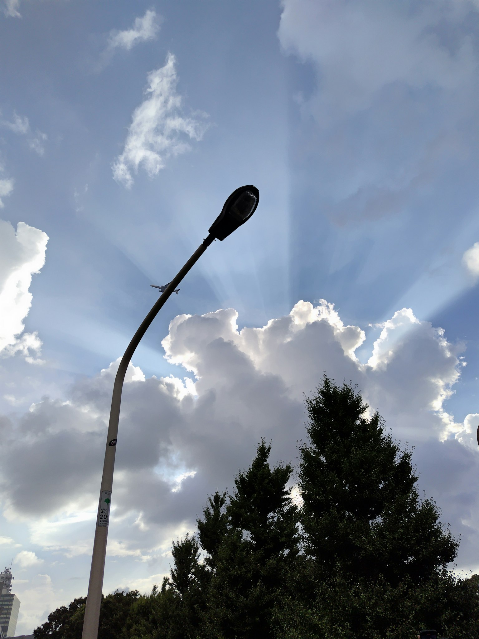 Farola frente a un cielo nublado con rayos de sol