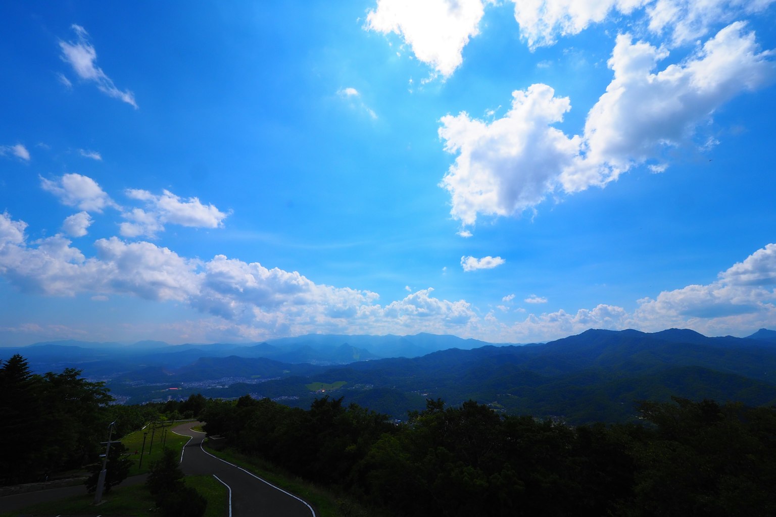 Pemandangan indah dengan langit biru awan putih gunung di kejauhan dan pohon hijau