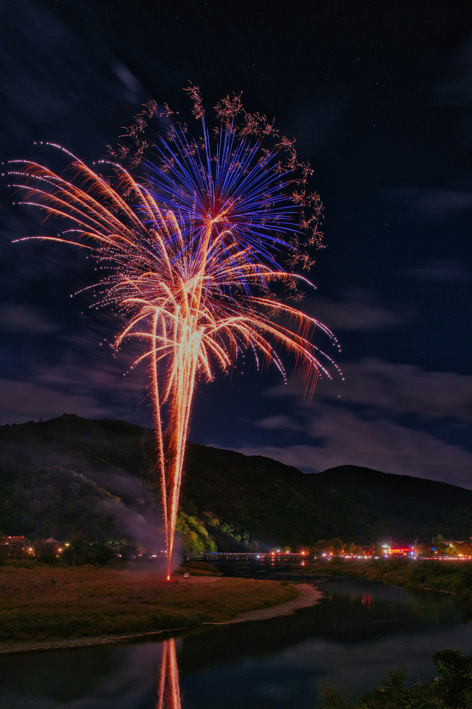 Colorful fireworks bursting in the night sky reflected in a calm river