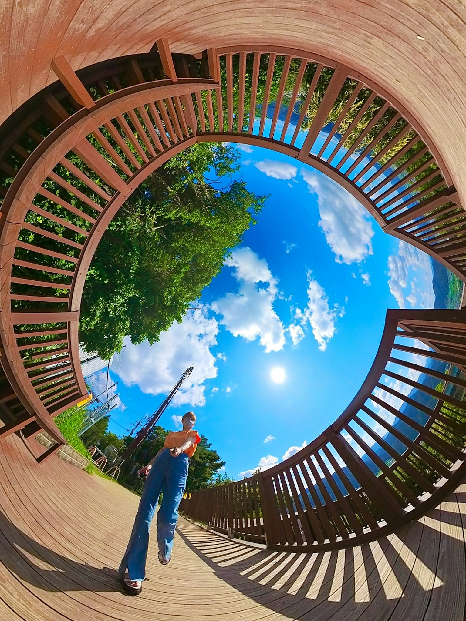 Panoramablick auf eine Person, die auf einer Holzterrasse unter blauem Himmel und Sonne steht