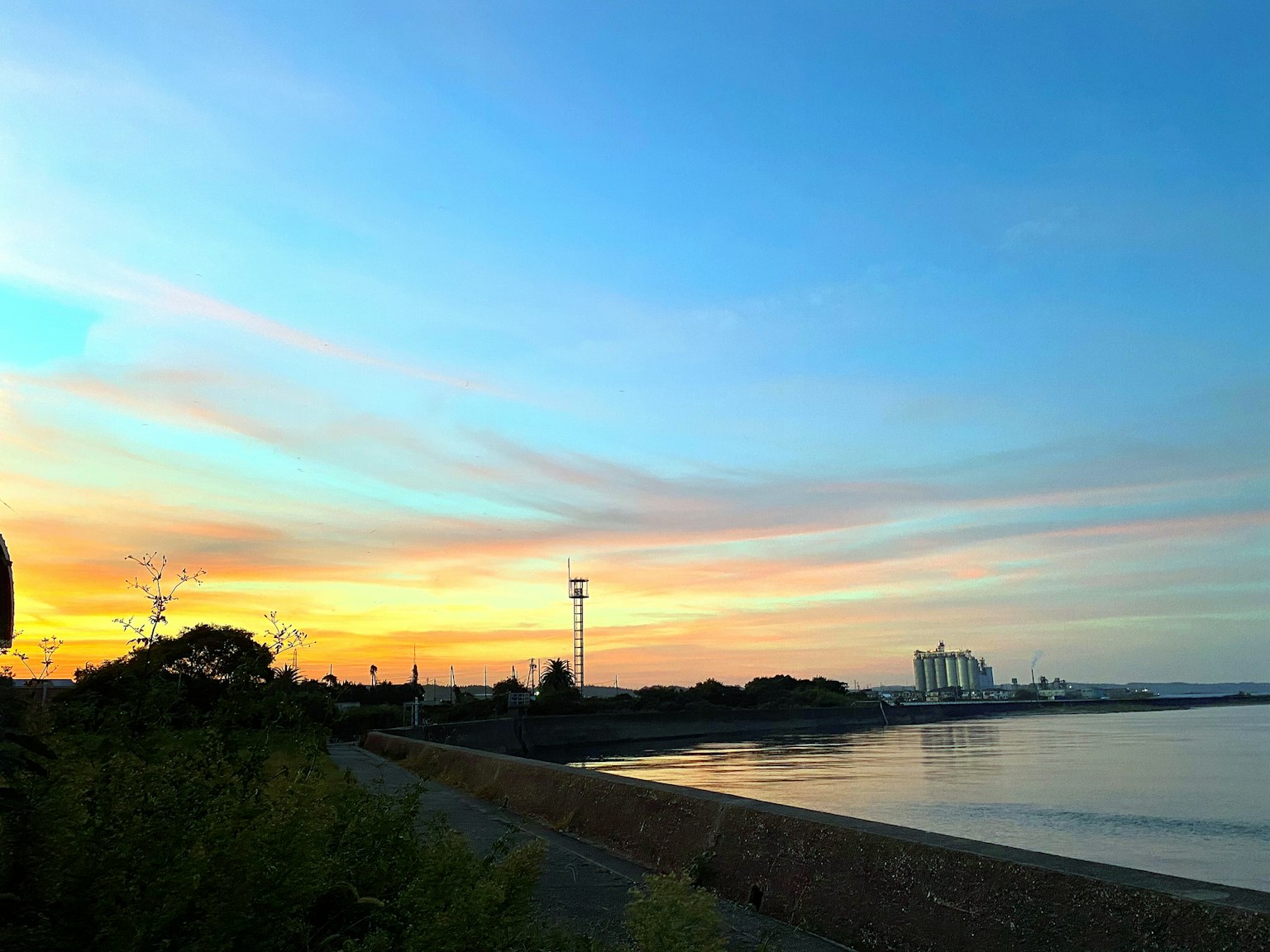 Scenic view of a coastline during sunset with distant buildings and towers