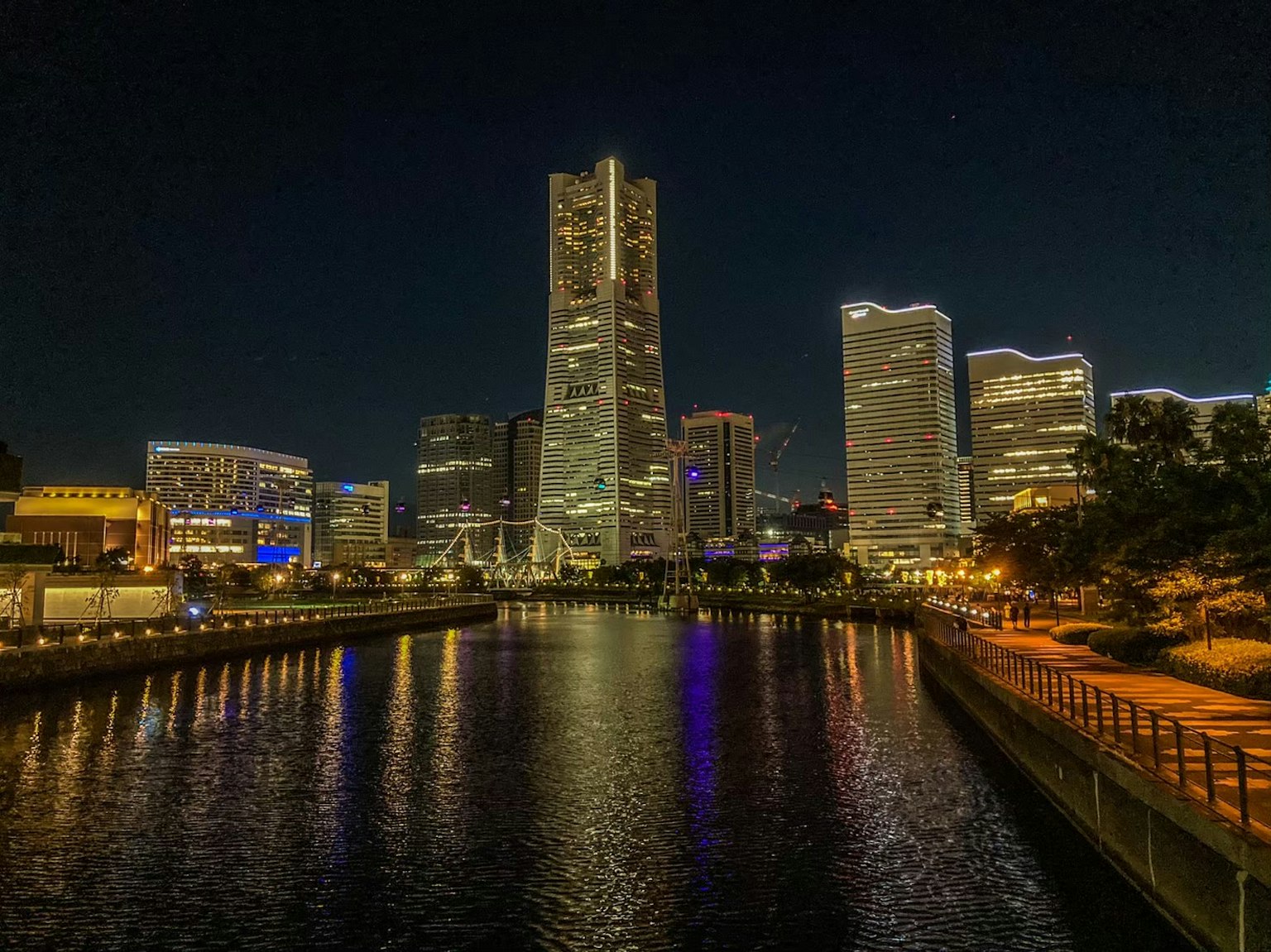 Skyline di Yokohama di notte con grattacieli illuminati e riflesso sull'acqua