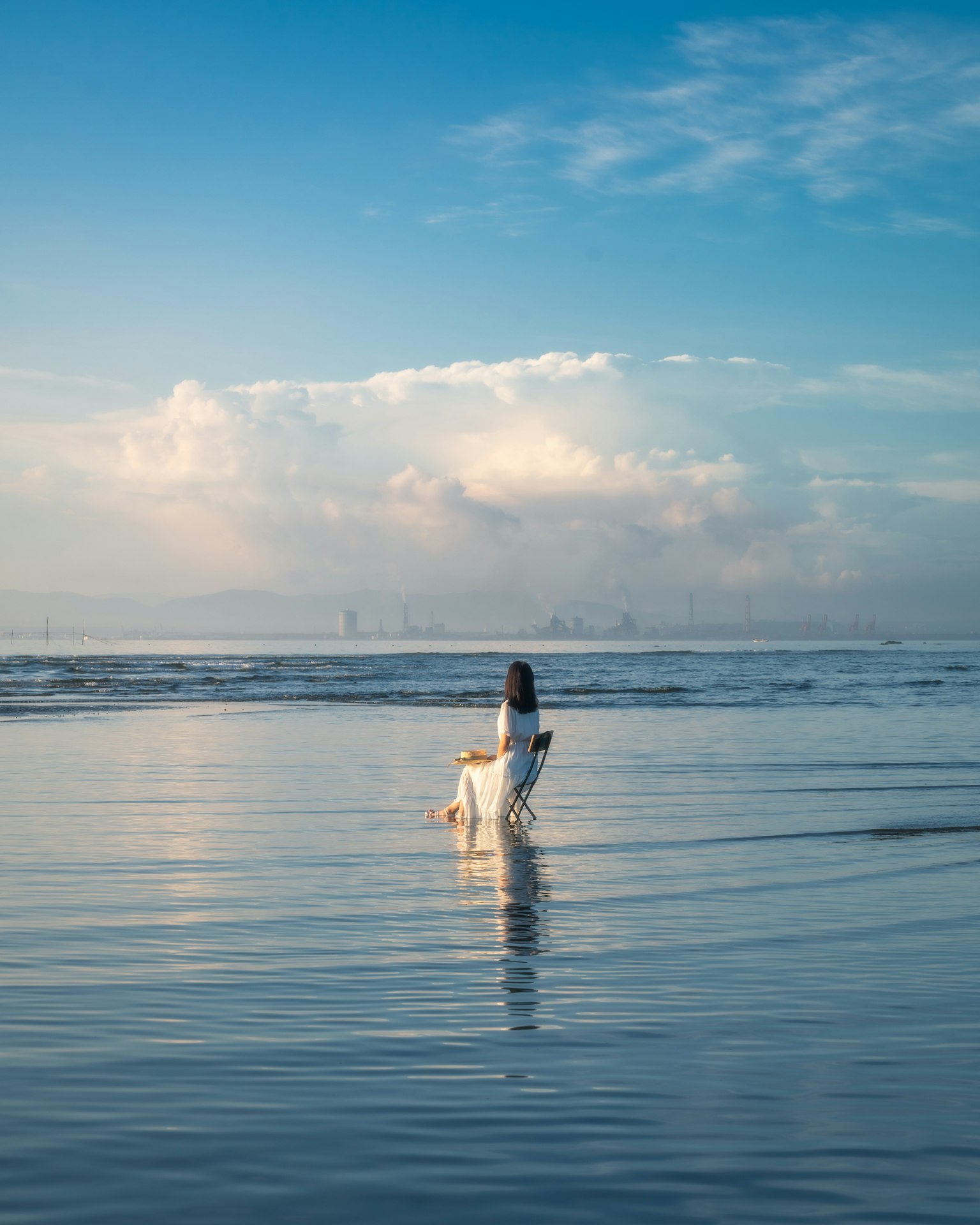 海邊玩狗的女性輪廓 背景是美麗的藍天和雲朵