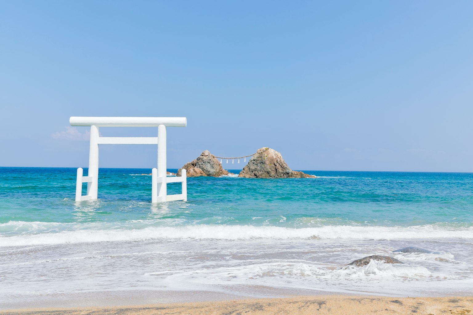 Scena di spiaggia con un torii bianco e un oceano blu