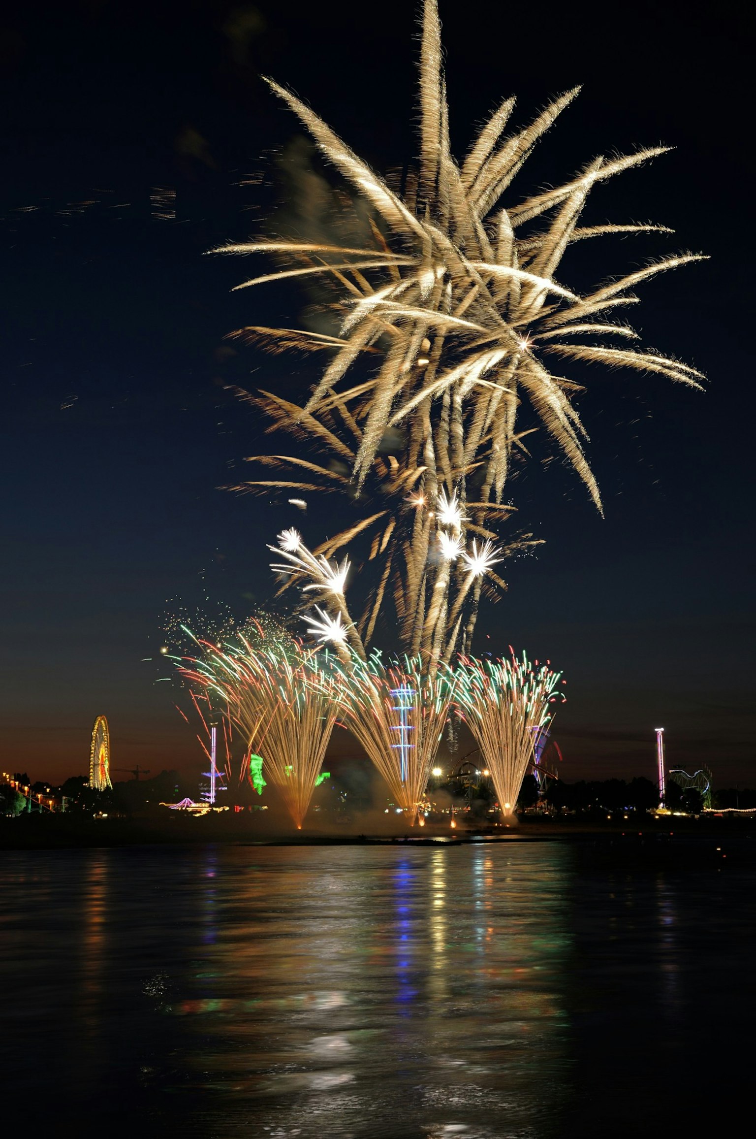 Des feux d'artifice éclatant dans le ciel nocturne avec des reflets sur l'eau