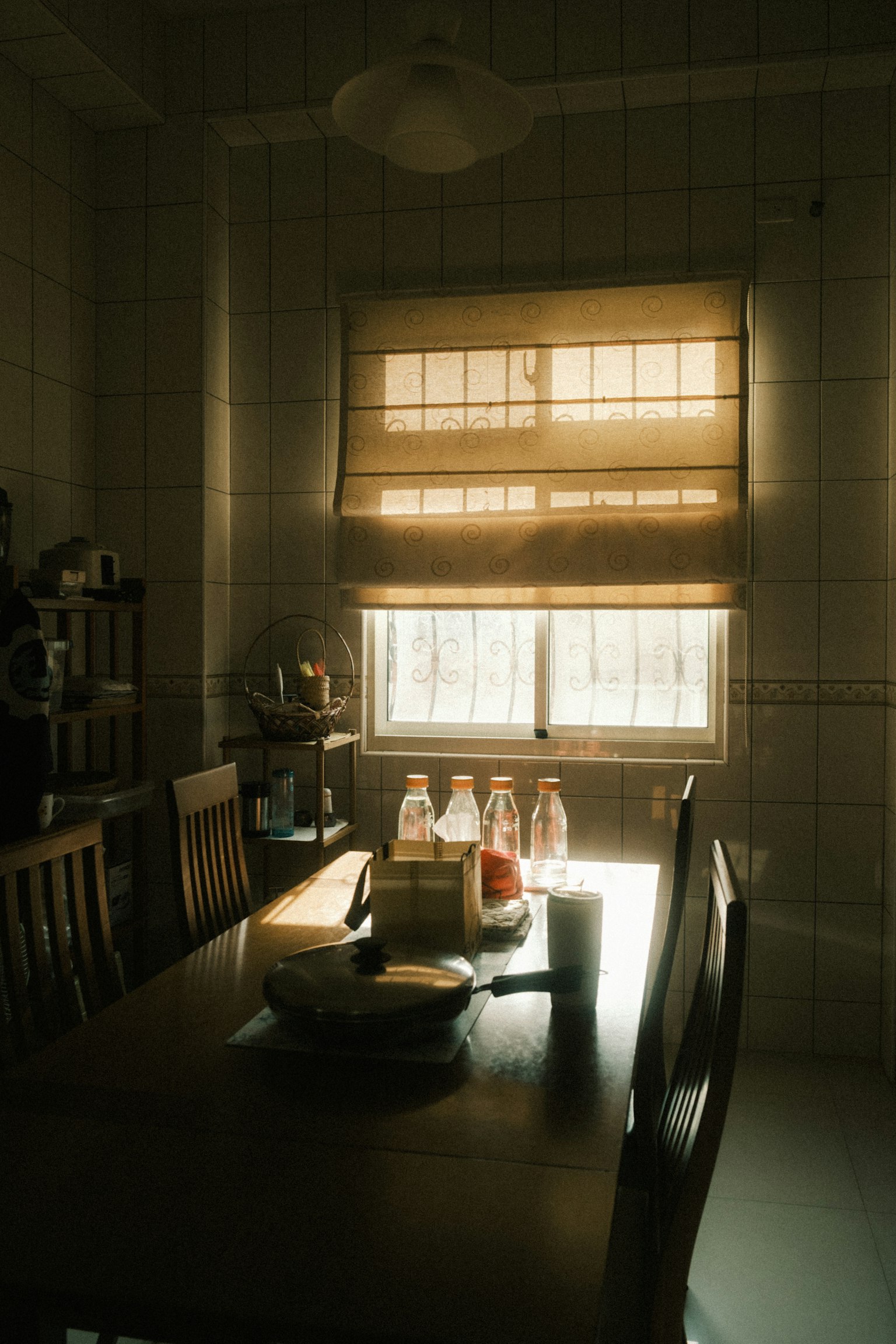 Intérieur d'une salle à manger avec une fenêtre lumineuse table en bois et chaises disposées stores de fenêtre fermés