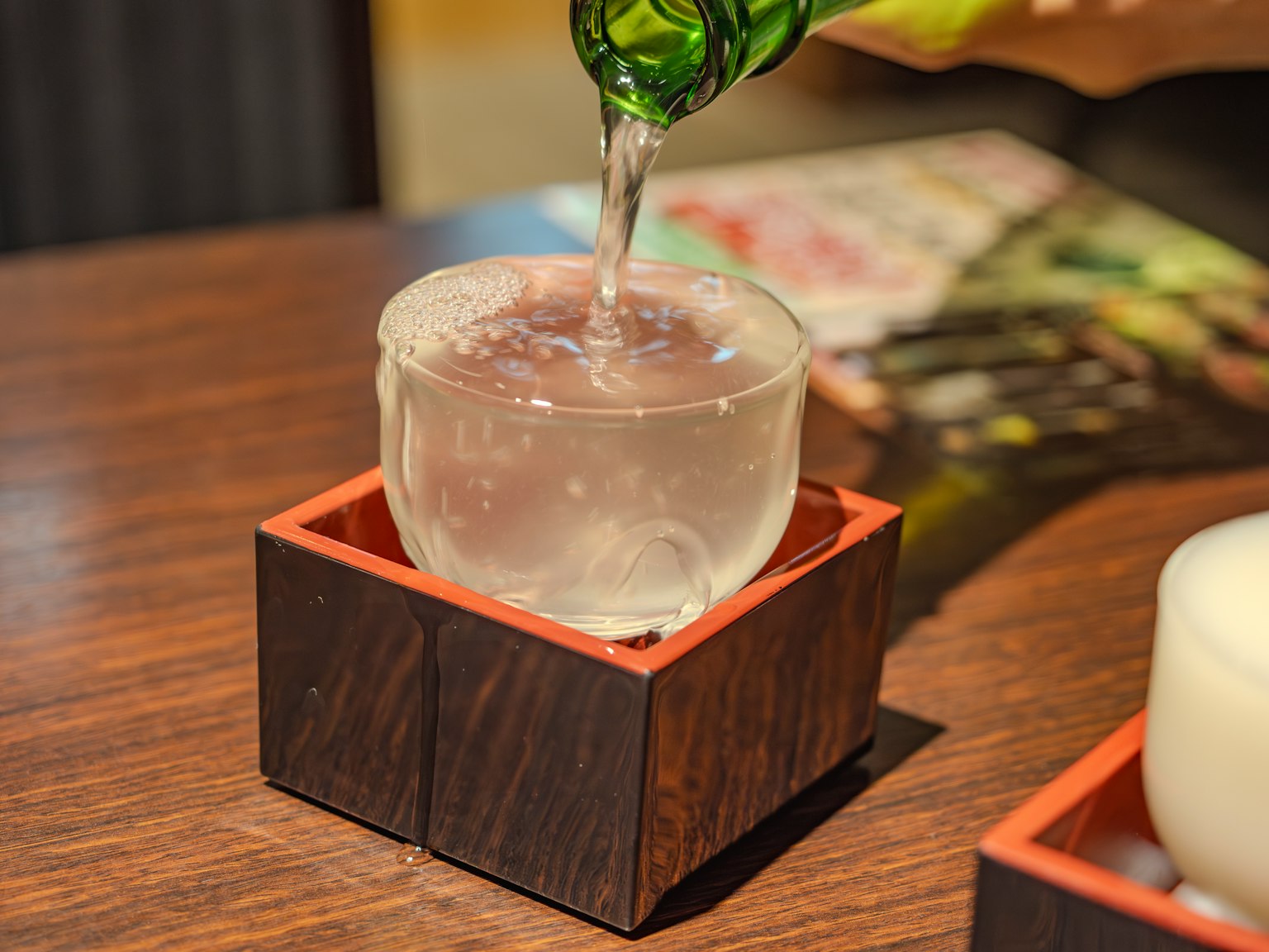 Clear drink being poured into a wooden cup