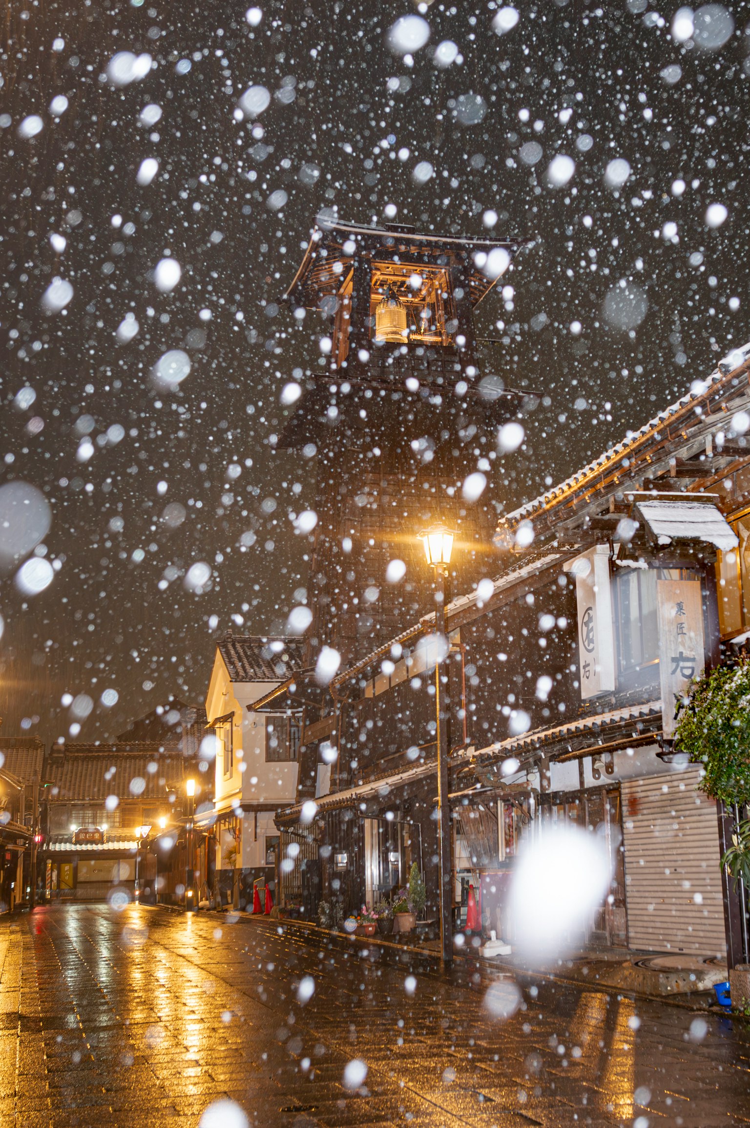 Neve che cade su una strada di notte con un campanile