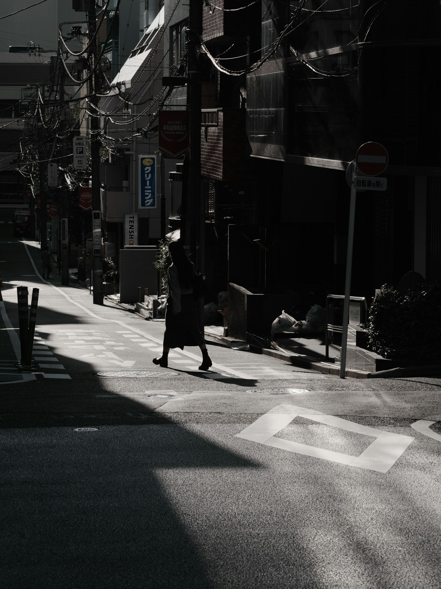 Silueta de una persona caminando en una calle oscura con líneas eléctricas prominentes