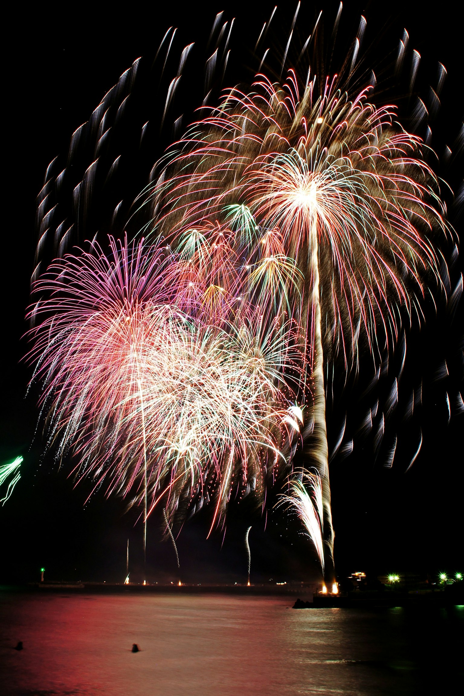 Fuochi d'artificio colorati che illuminano il cielo notturno riflessi sull'acqua