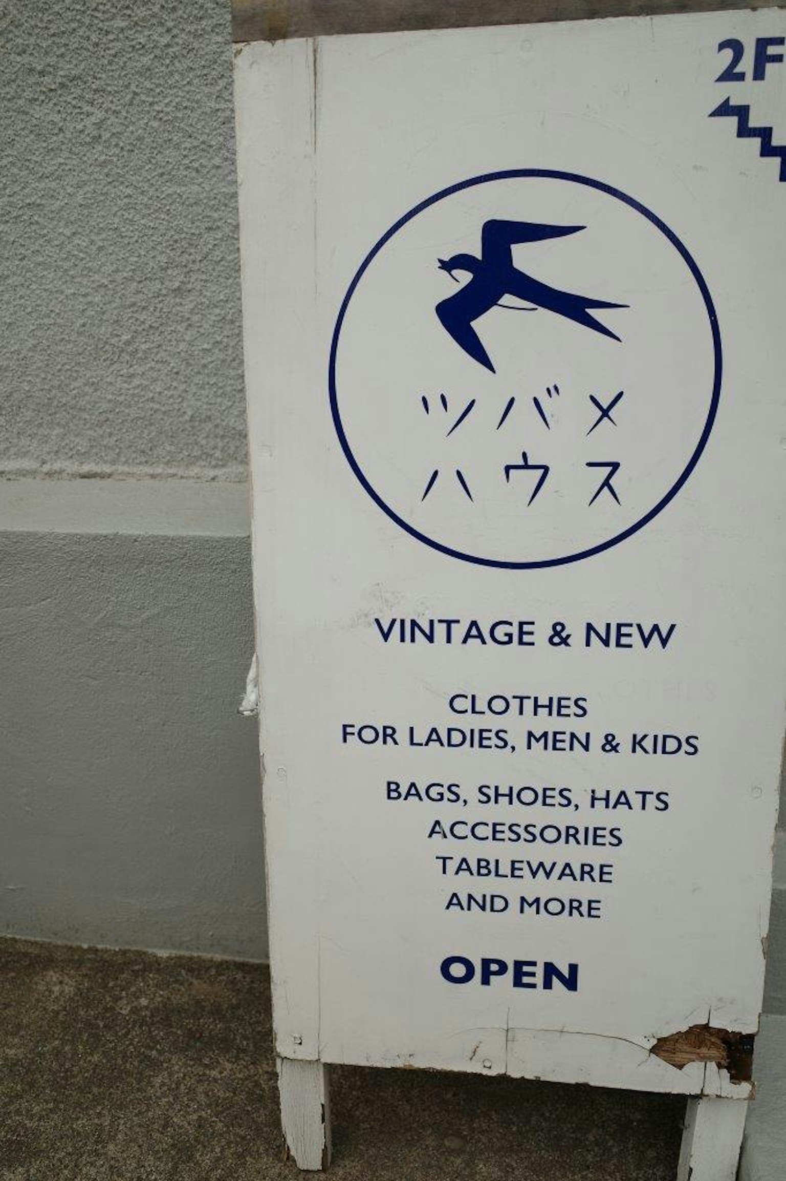 一家复古和新衣服商店的招牌，展示女性、男性和儿童的服装以及包、鞋、帽、配饰和餐具