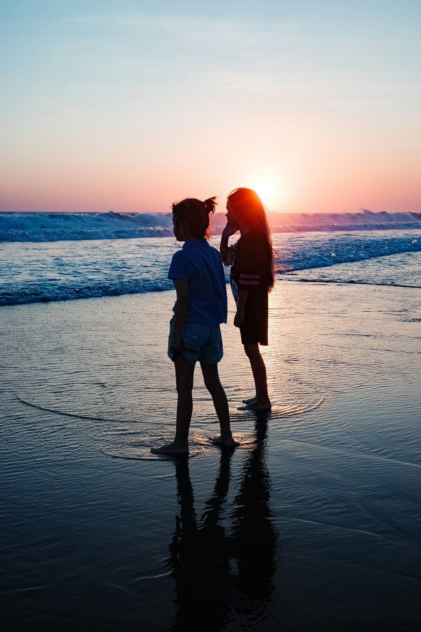 夕日に照らされる海辺で寄り添うカップル
