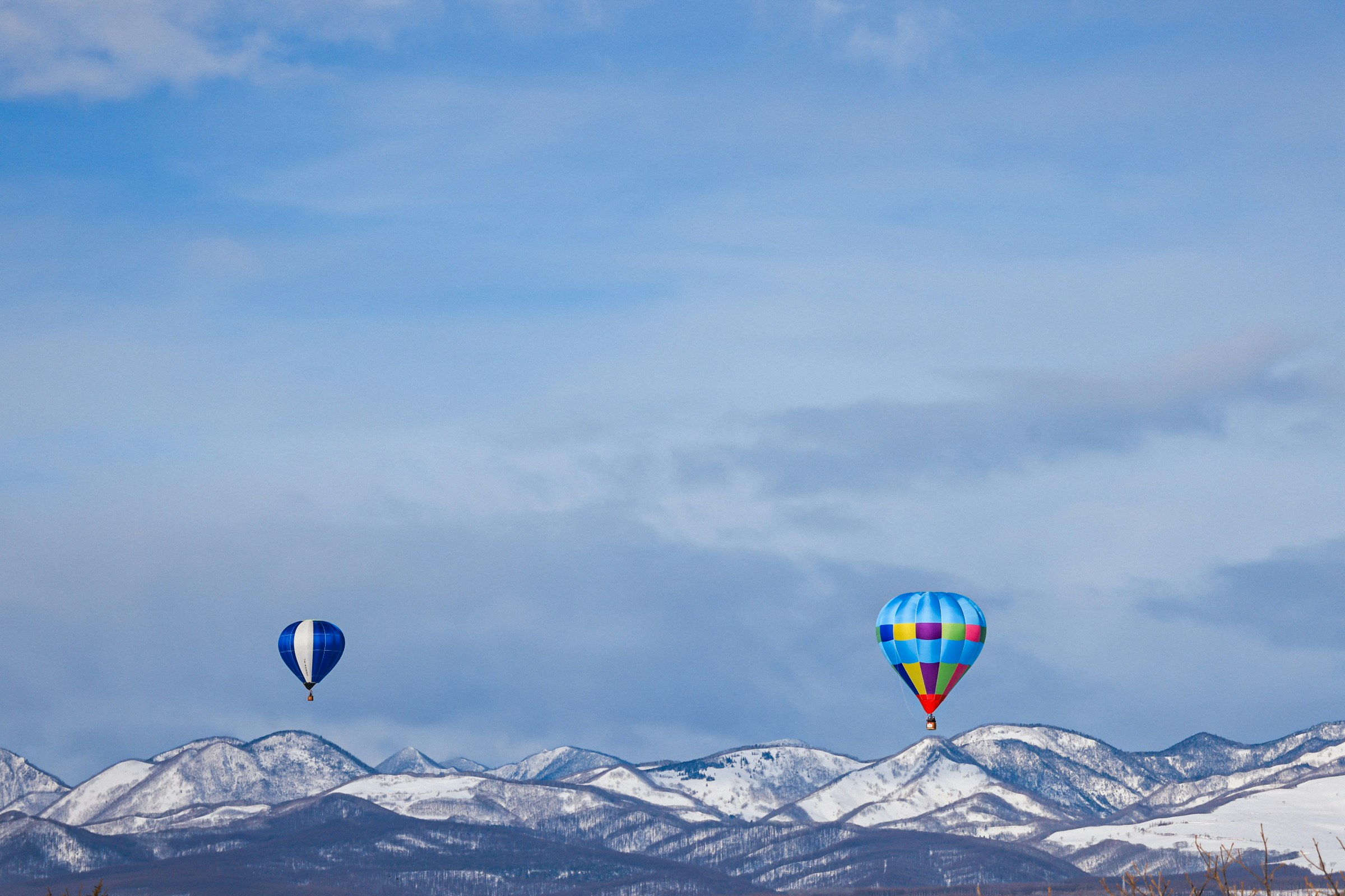 hot air balloons over snowy mountain ridges