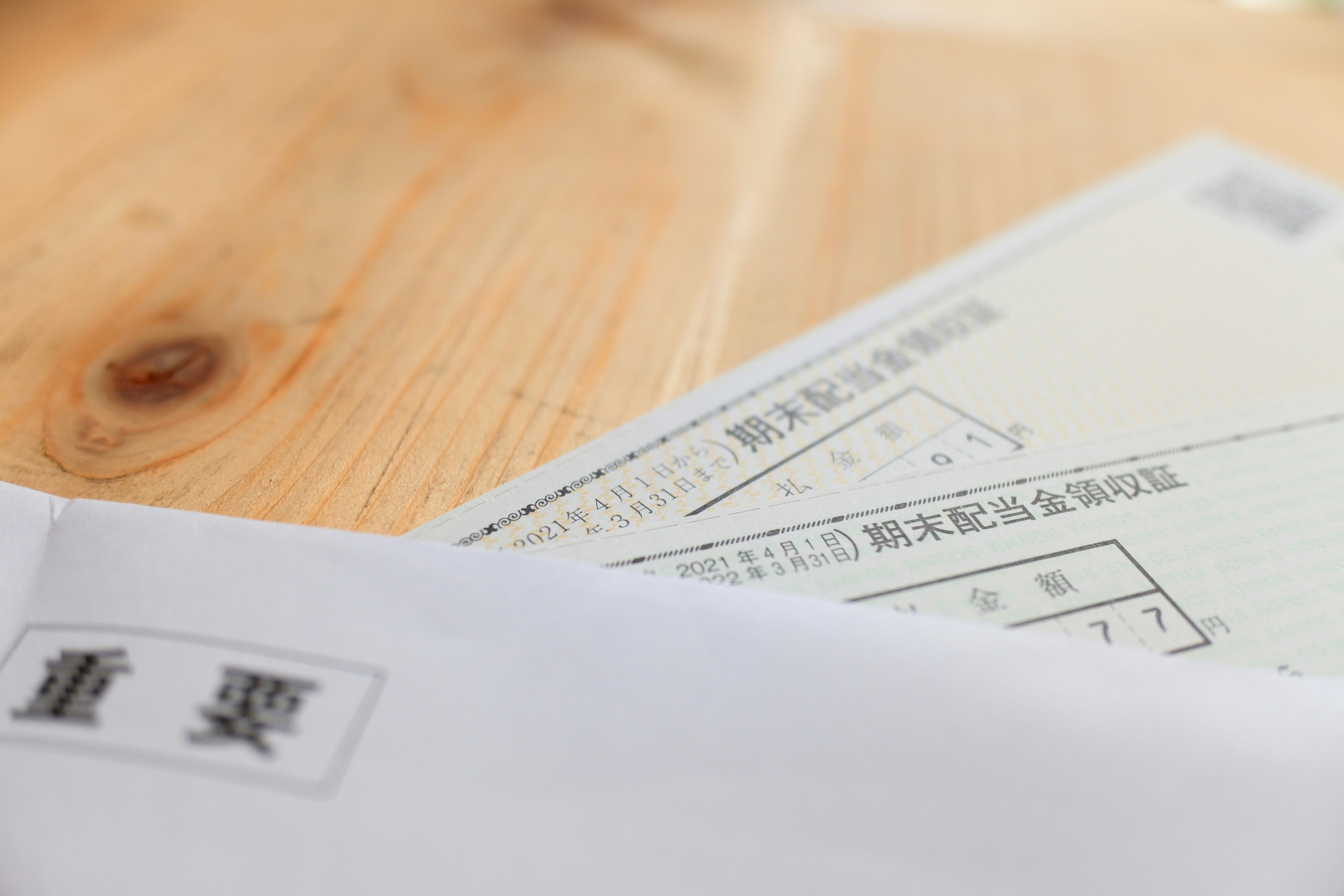 木目の机の上に置かれた書類と封筒