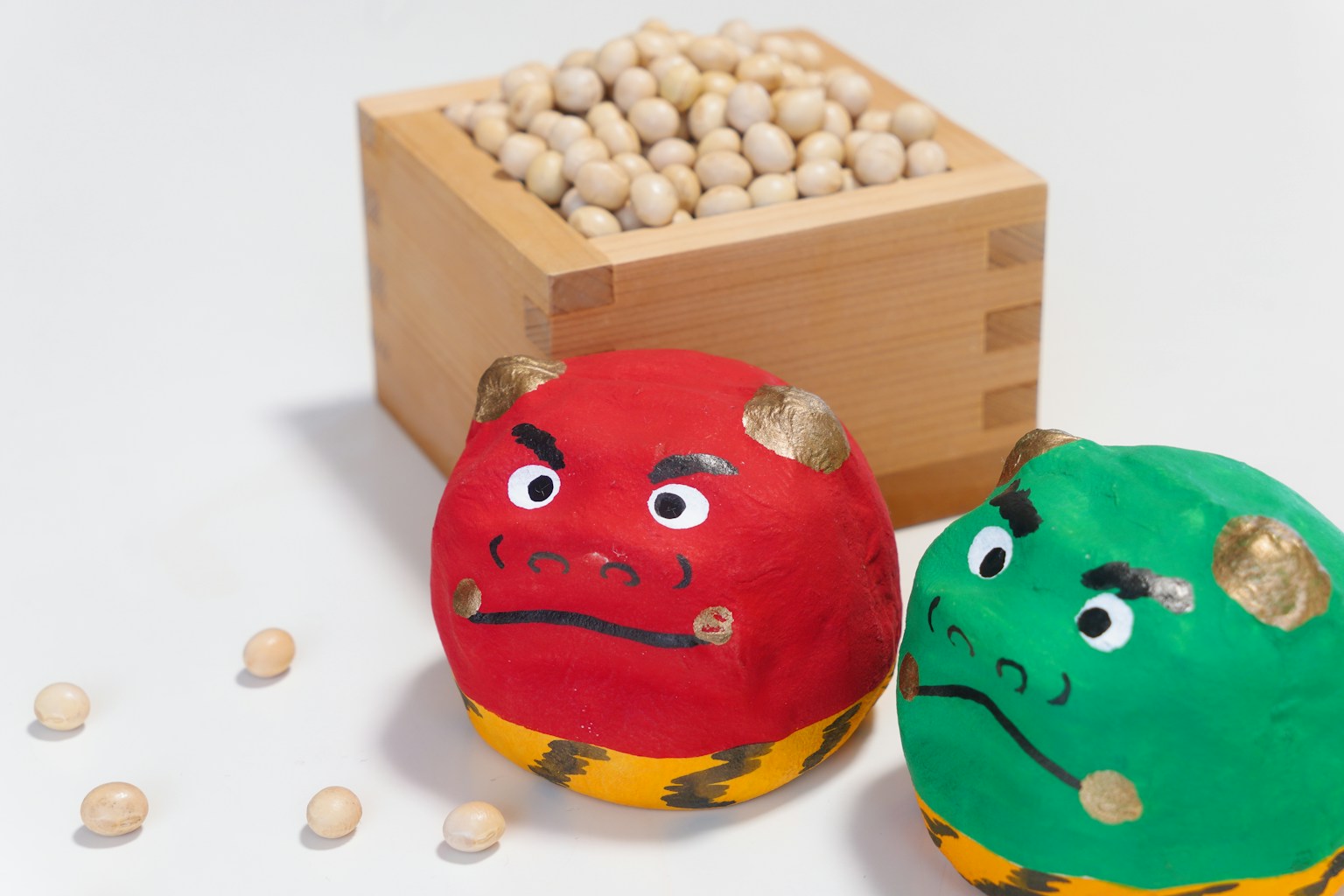 Giocattoli a forma di demoni rosso e verde con una scatola di legno di fagioli