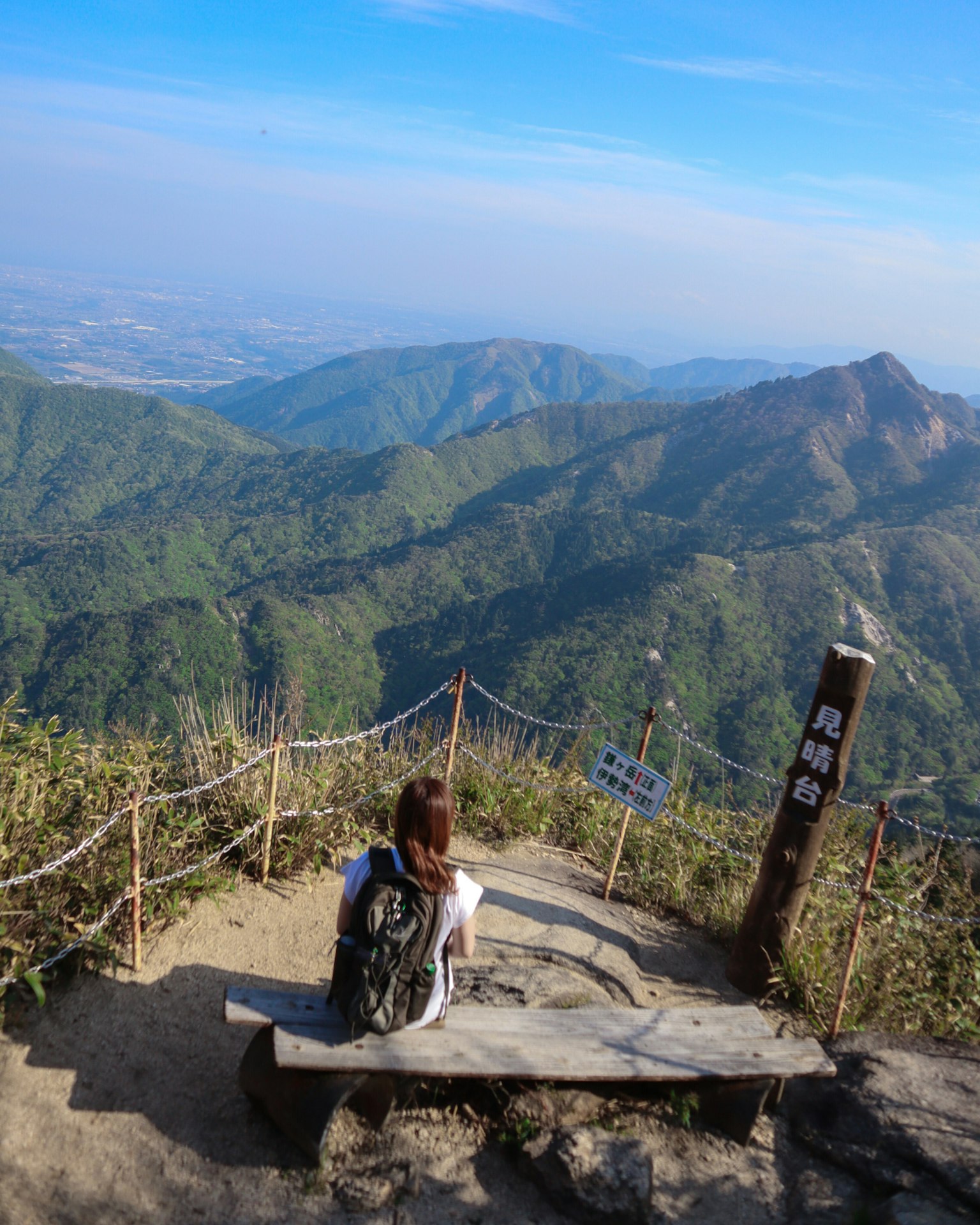 Donna seduta sulla cima della montagna con vista sulle colline verdi