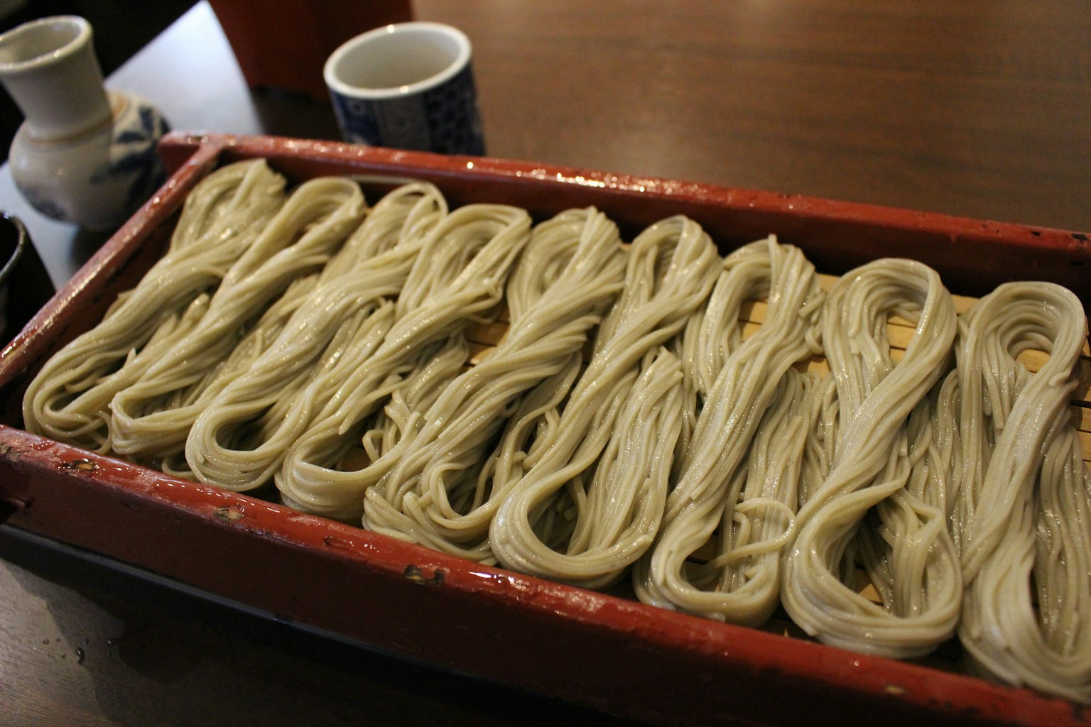Una bandeja de madera llena de fideos soba dispuestos ordenadamente