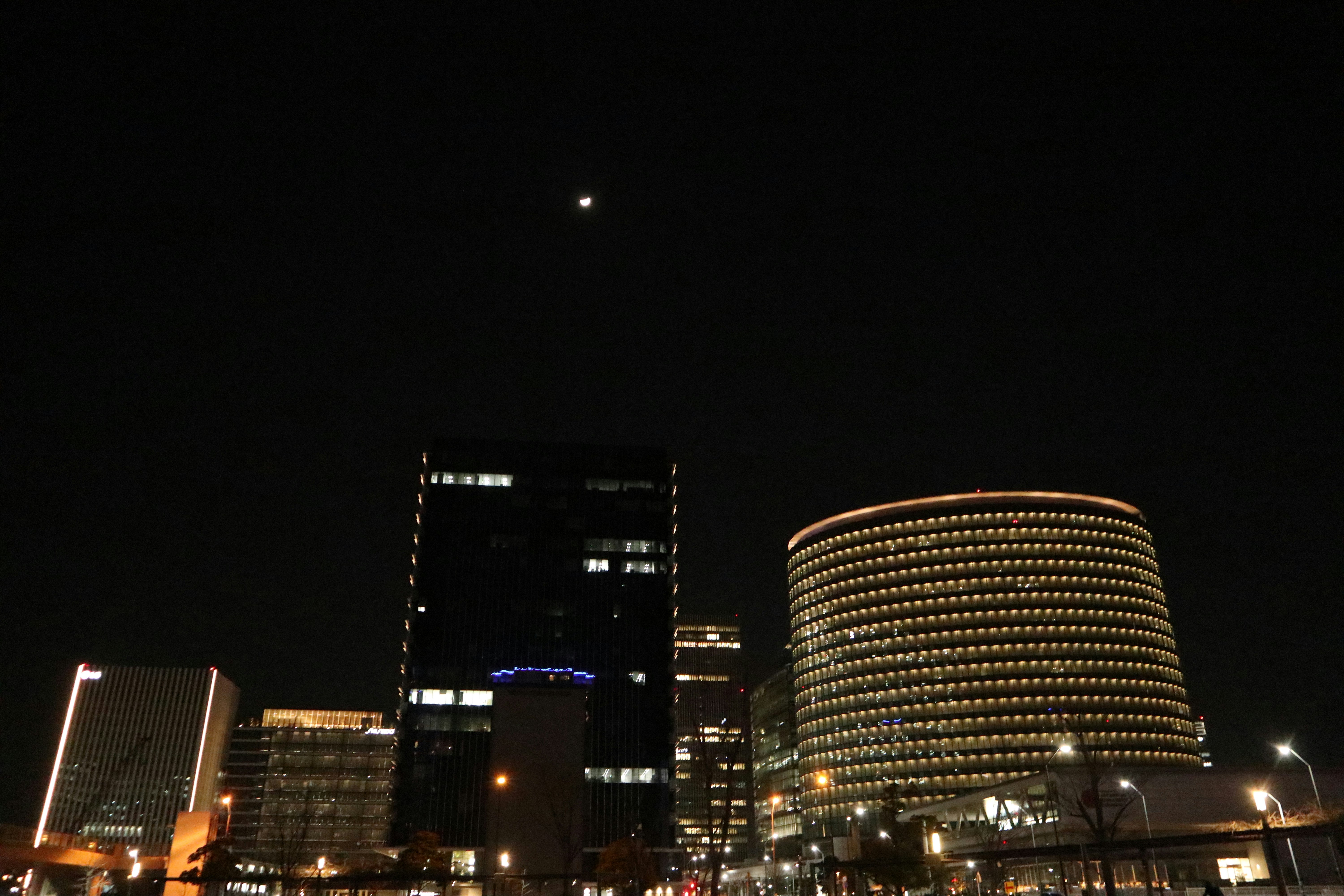 night skyline of high-rise buildings and a round glass tower