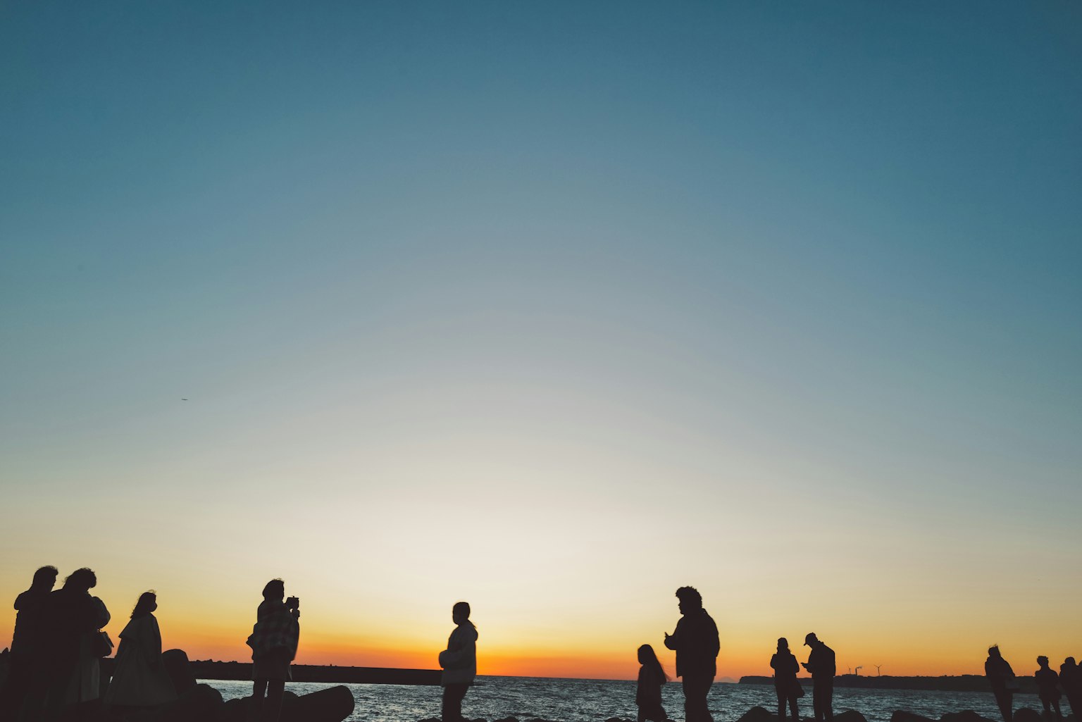 Siluet orang di pantai saat matahari terbenam yang indah