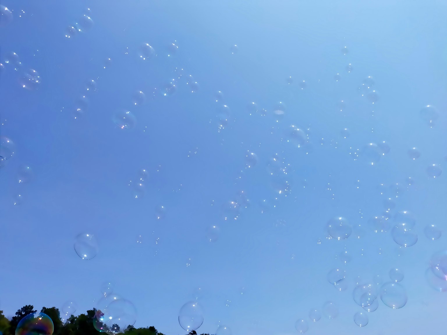 Seifenblasen, die in einem klaren blauen Himmel schweben